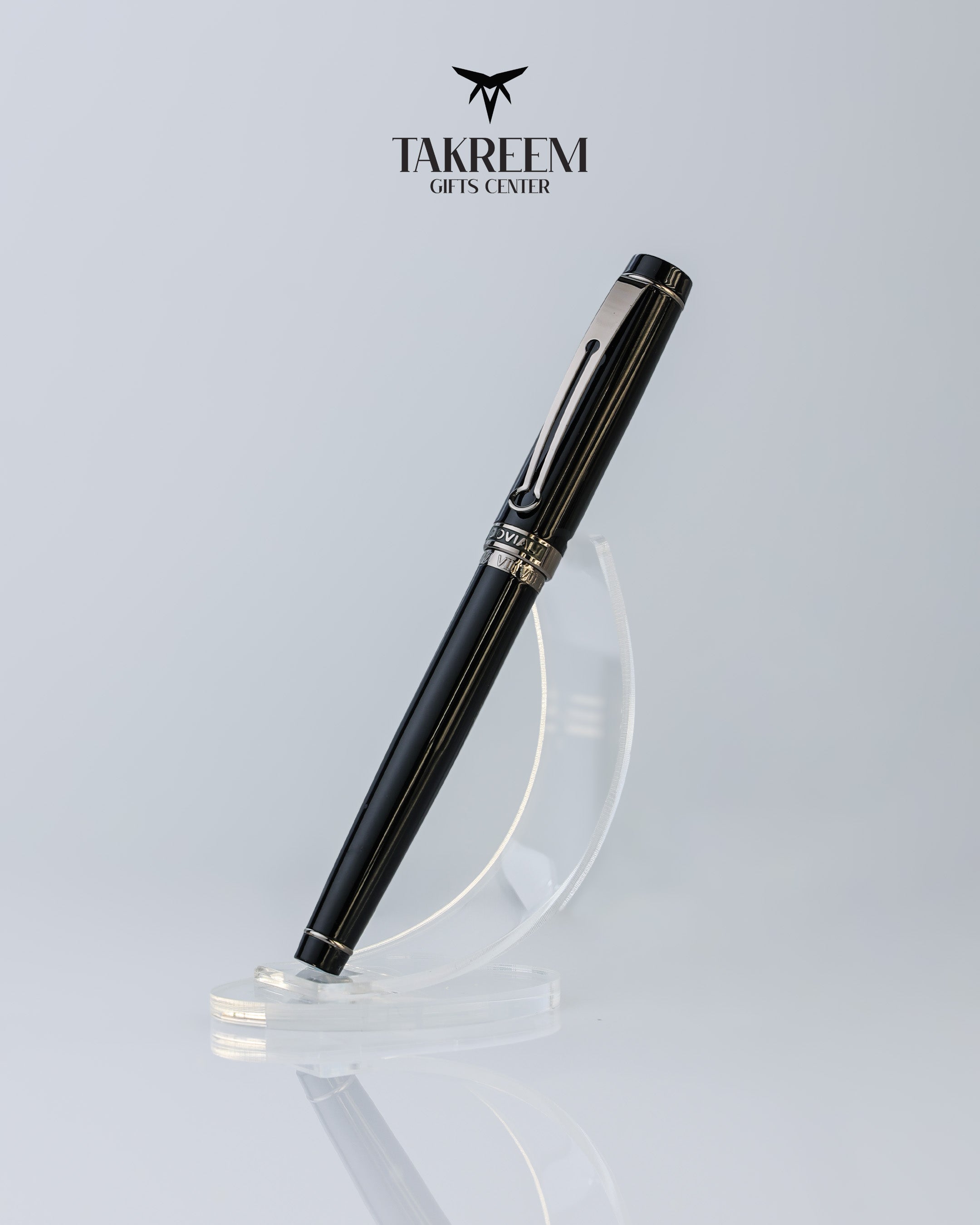 Black pen with silver accents on a clear stand against a light gray background, featuring the Takreem logo.