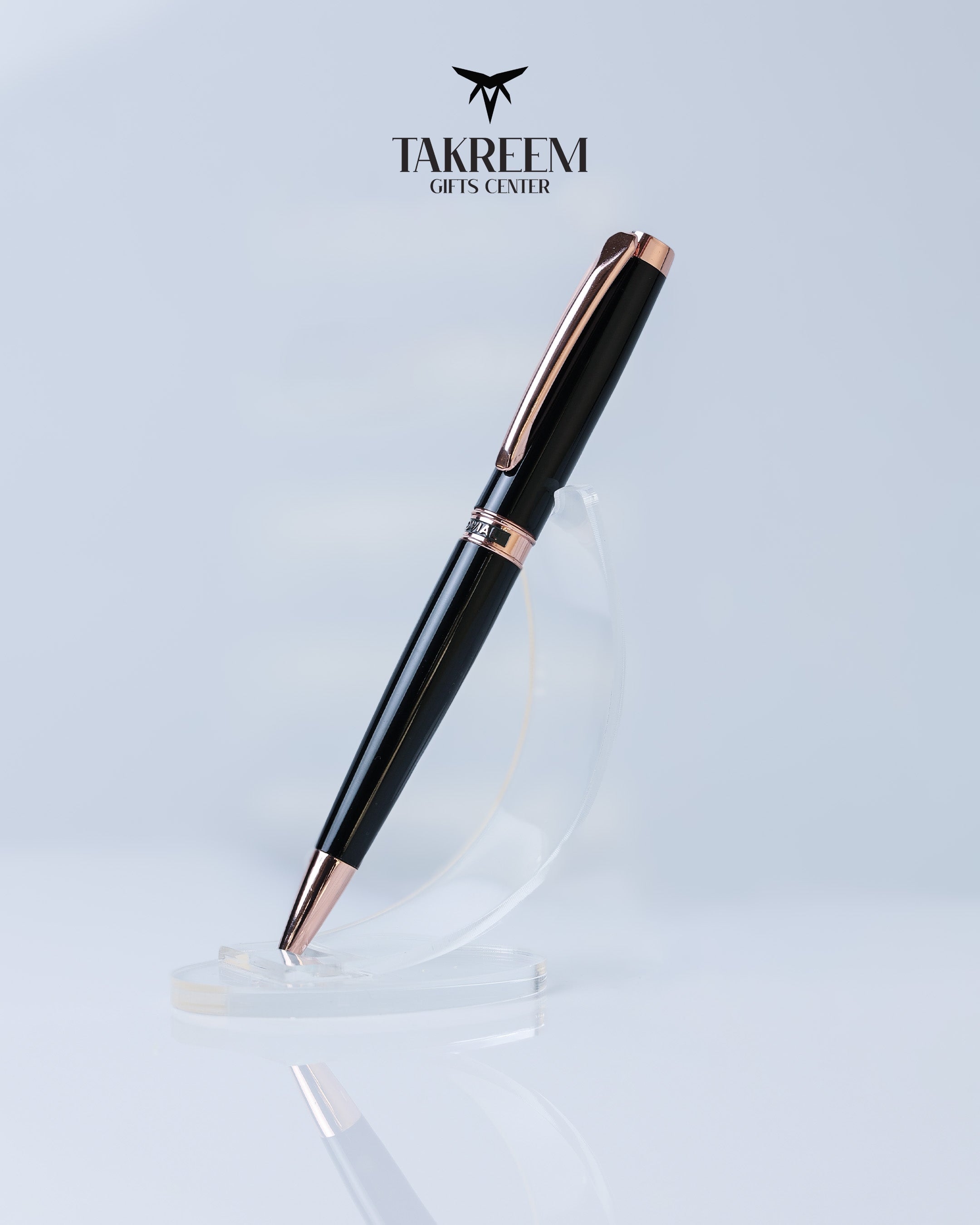 Black and rose gold pen on a clear stand with 'Takreem Gifts Center' branding.