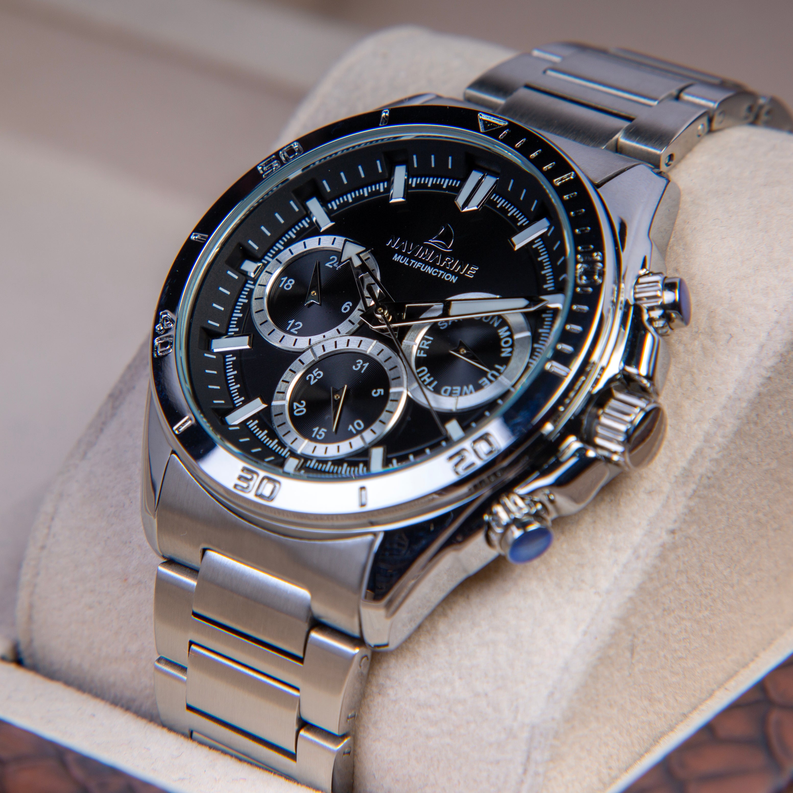 Silver wristwatch with black face on a beige cushion