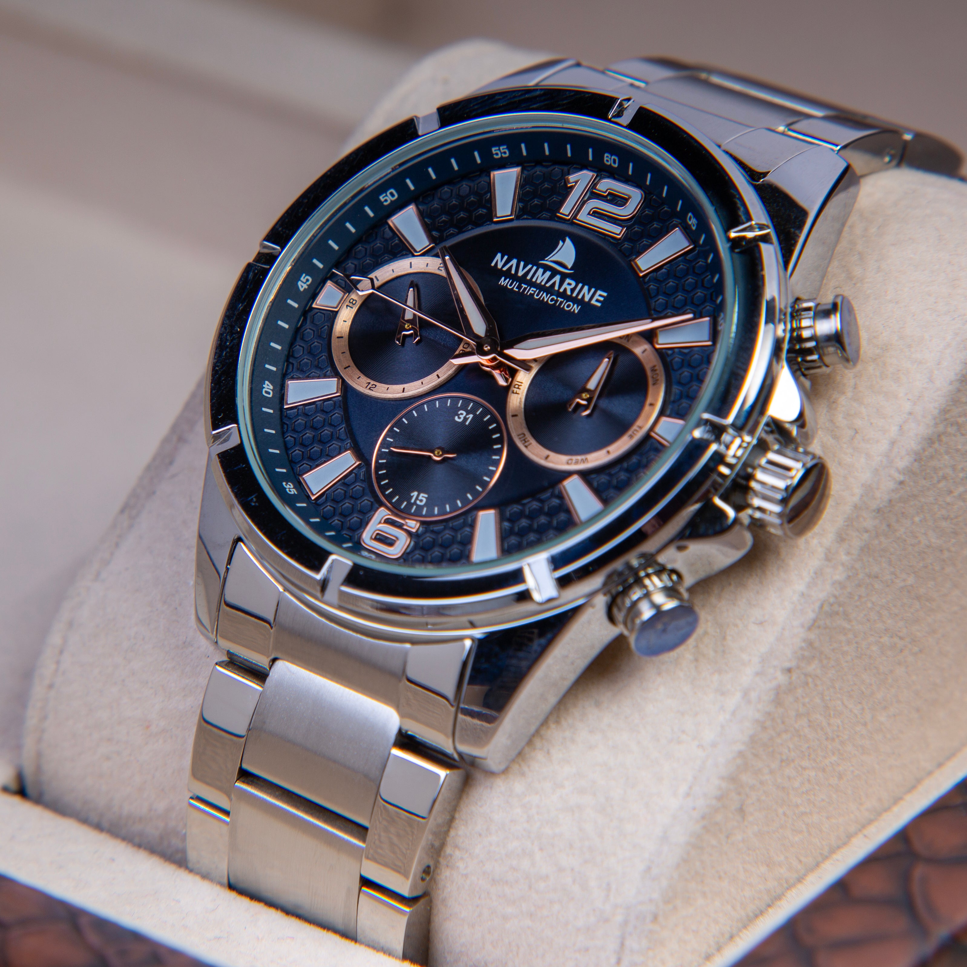 Luxury watch with blue face and silver metal strap on a soft surface