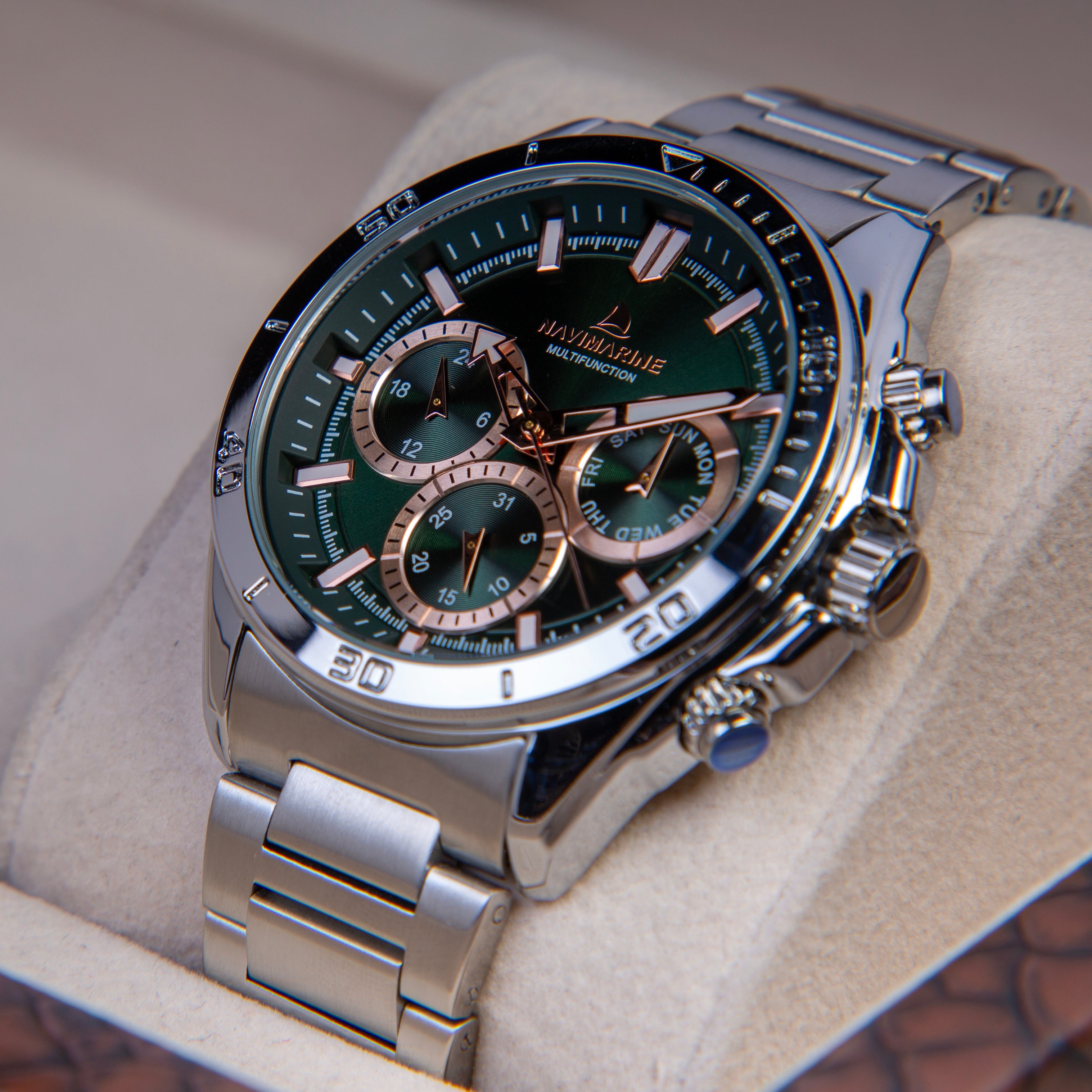 Silver watch with a green face on a beige cushion