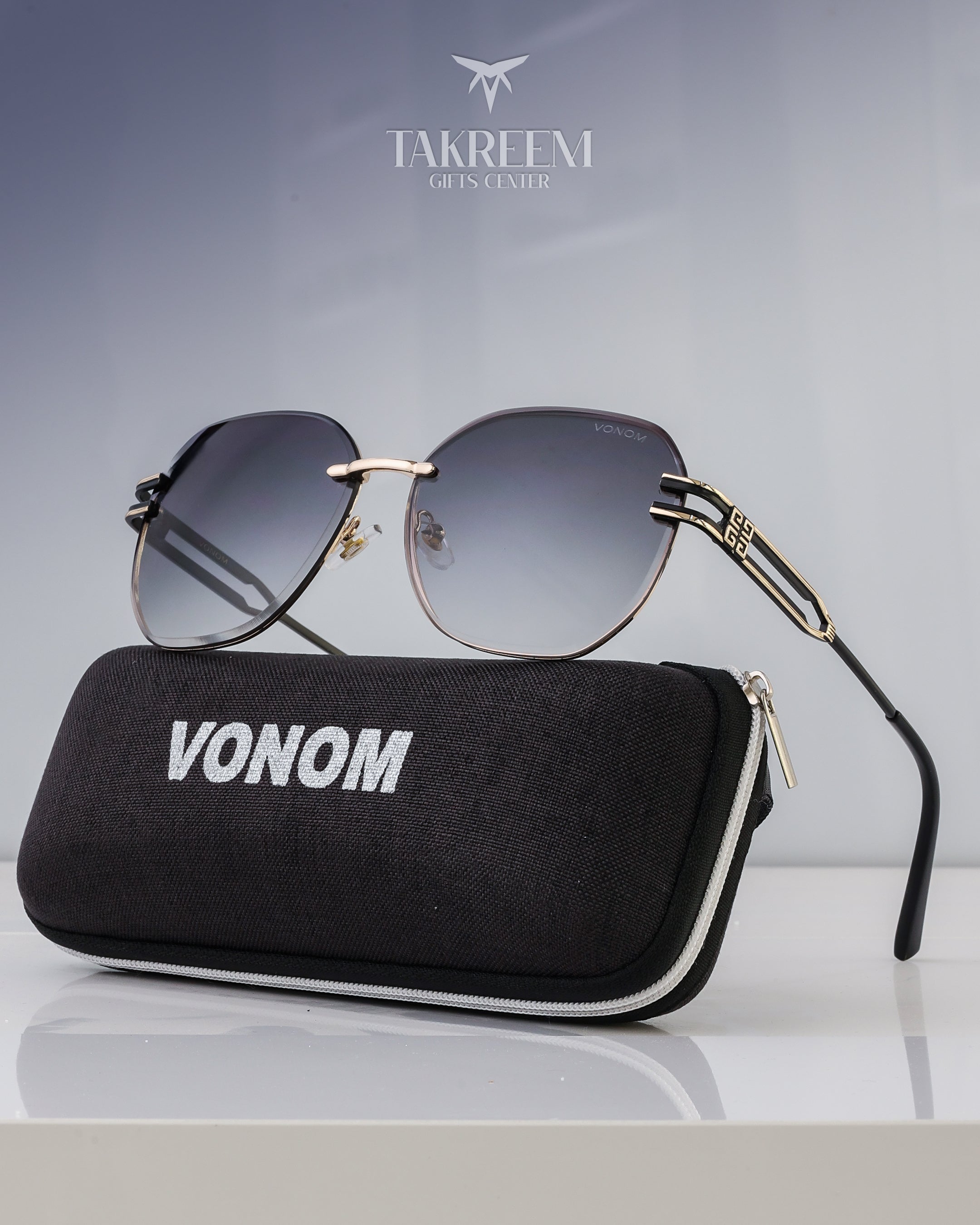 Sunglasses with a black case labeled 'VONOM' on a reflective surface with a gray gradient background.