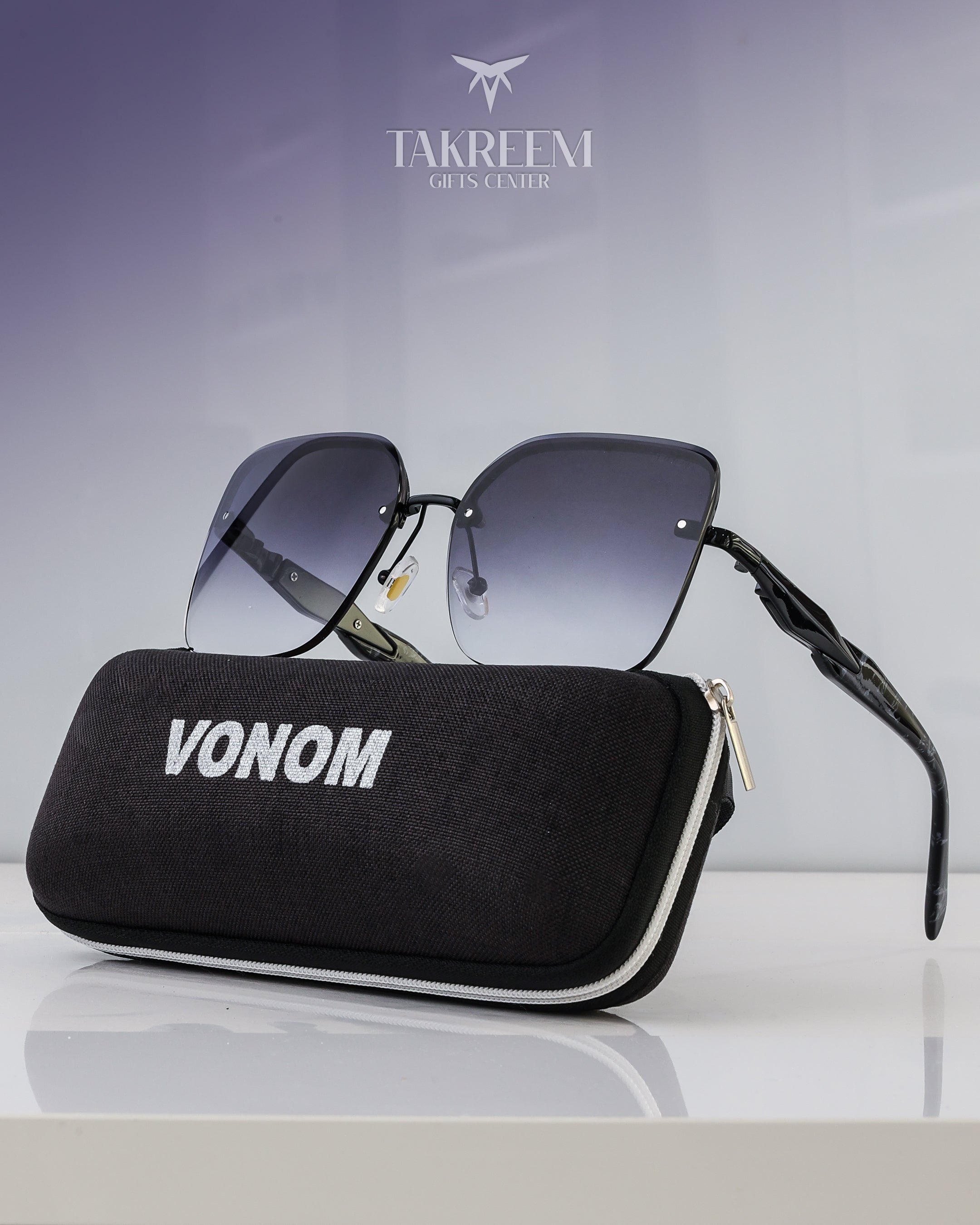 Black sunglasses with gradient lenses and a black case labeled 'VONOM' on a light gray background.
