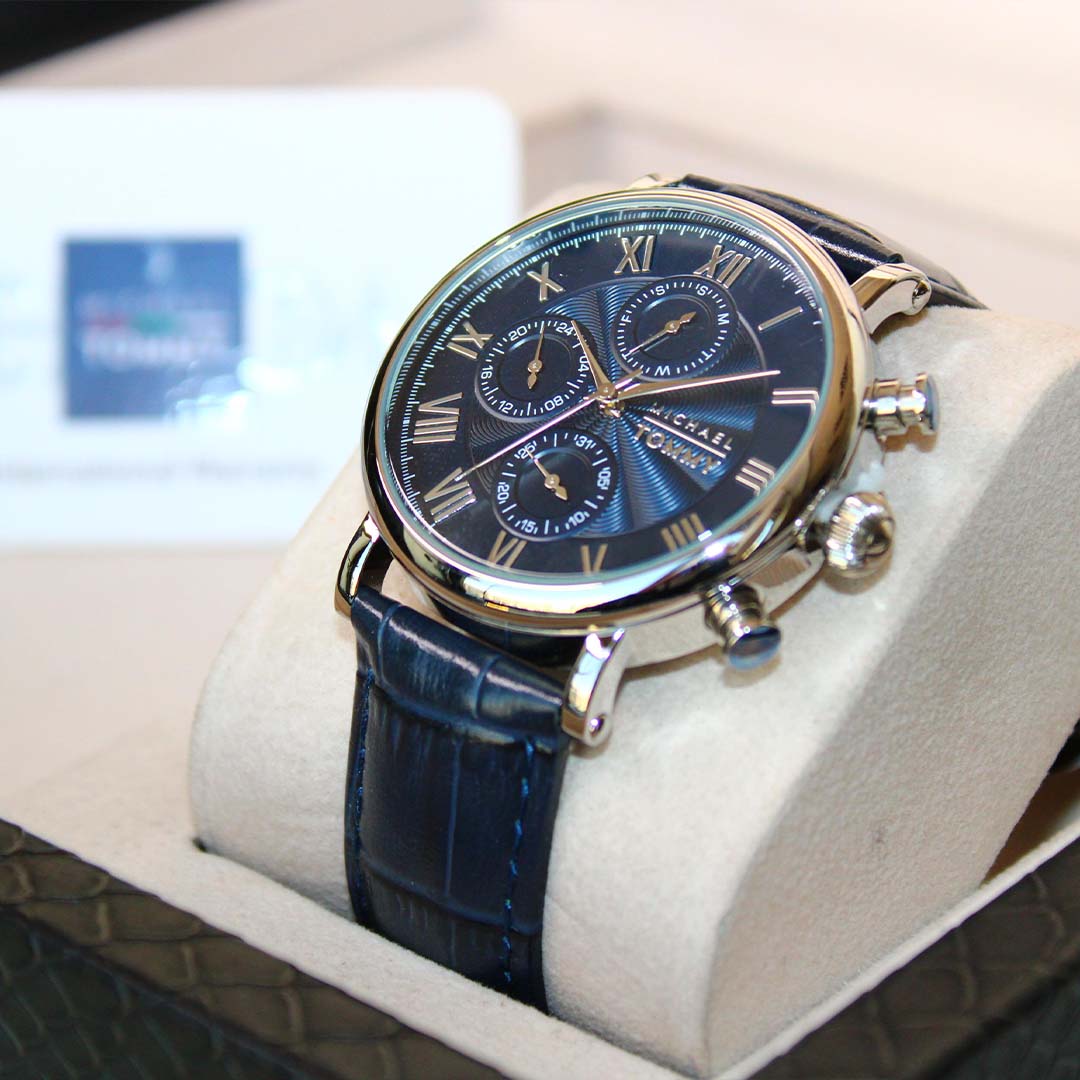 Luxury watch with blue strap and detailed face on a white cushion