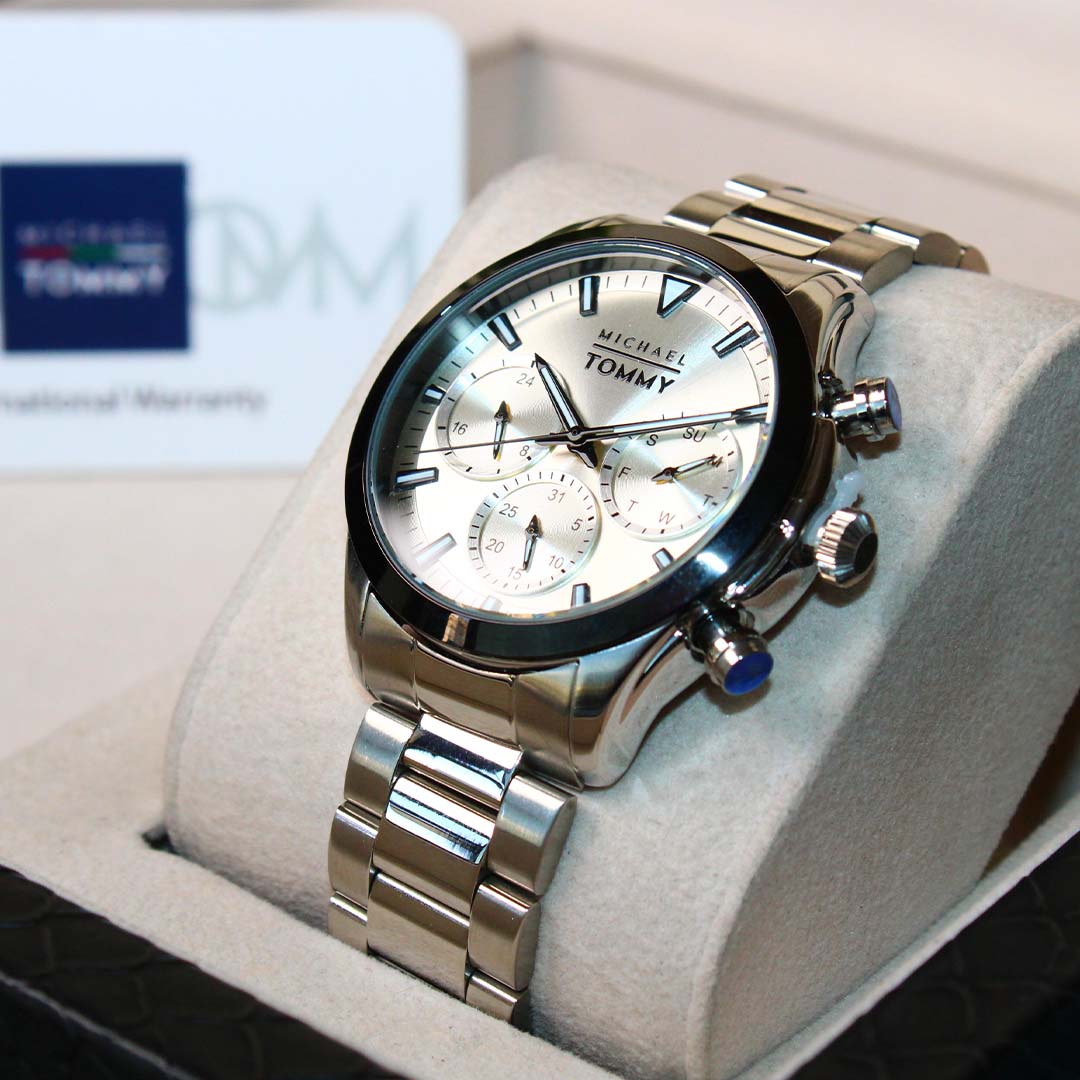 Silver Michael Kors watch on a white cushion with a blurred background