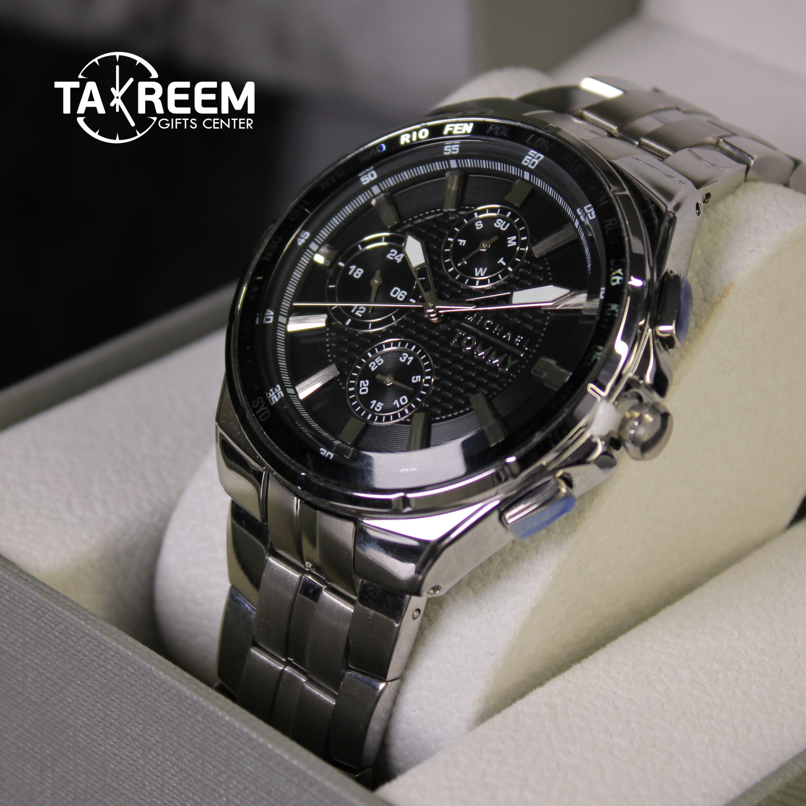 Silver wristwatch with black face in a box, brand 'Takreem' visible