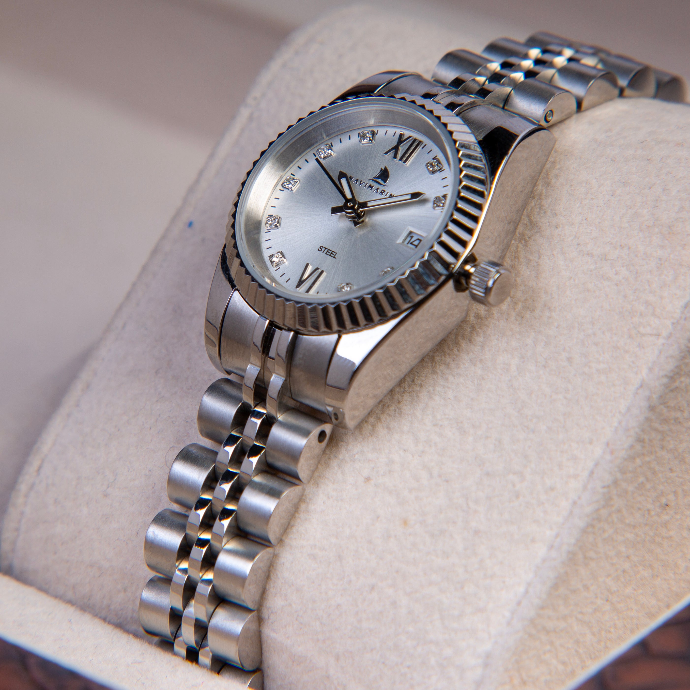 Silver wristwatch with a detailed face on a soft beige background