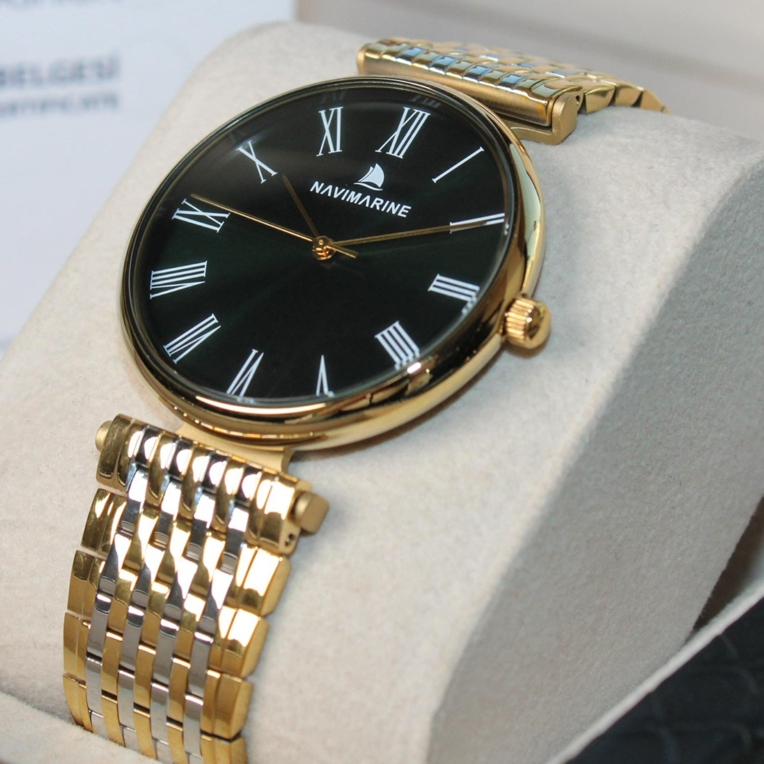 Gold wristwatch with black dial on a white cushion