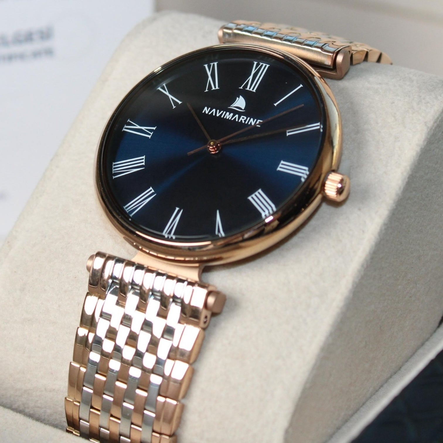 Navimarine watch with rose gold strap and blue dial on a light gray cushion