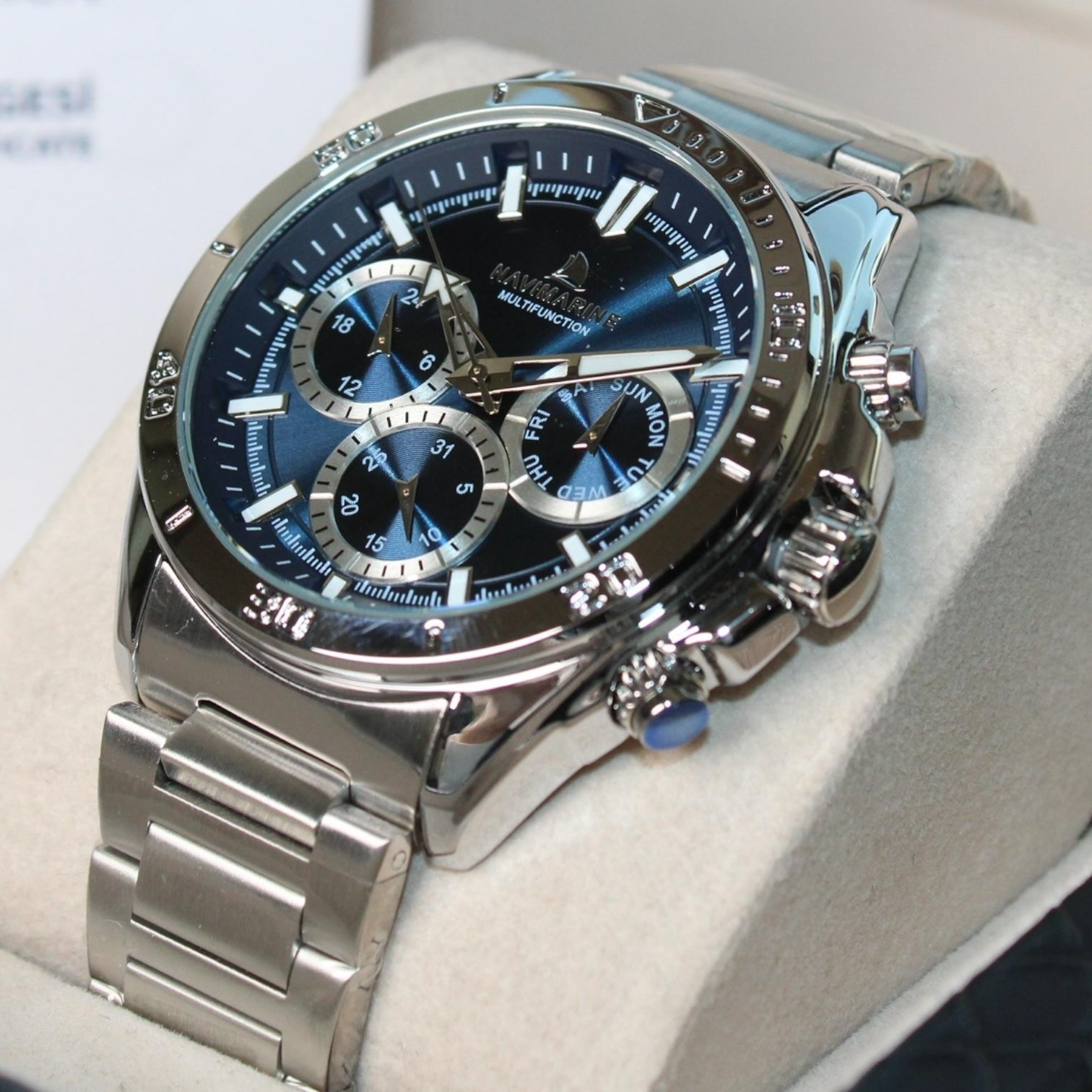 Silver watch with a blue face on a white cushion