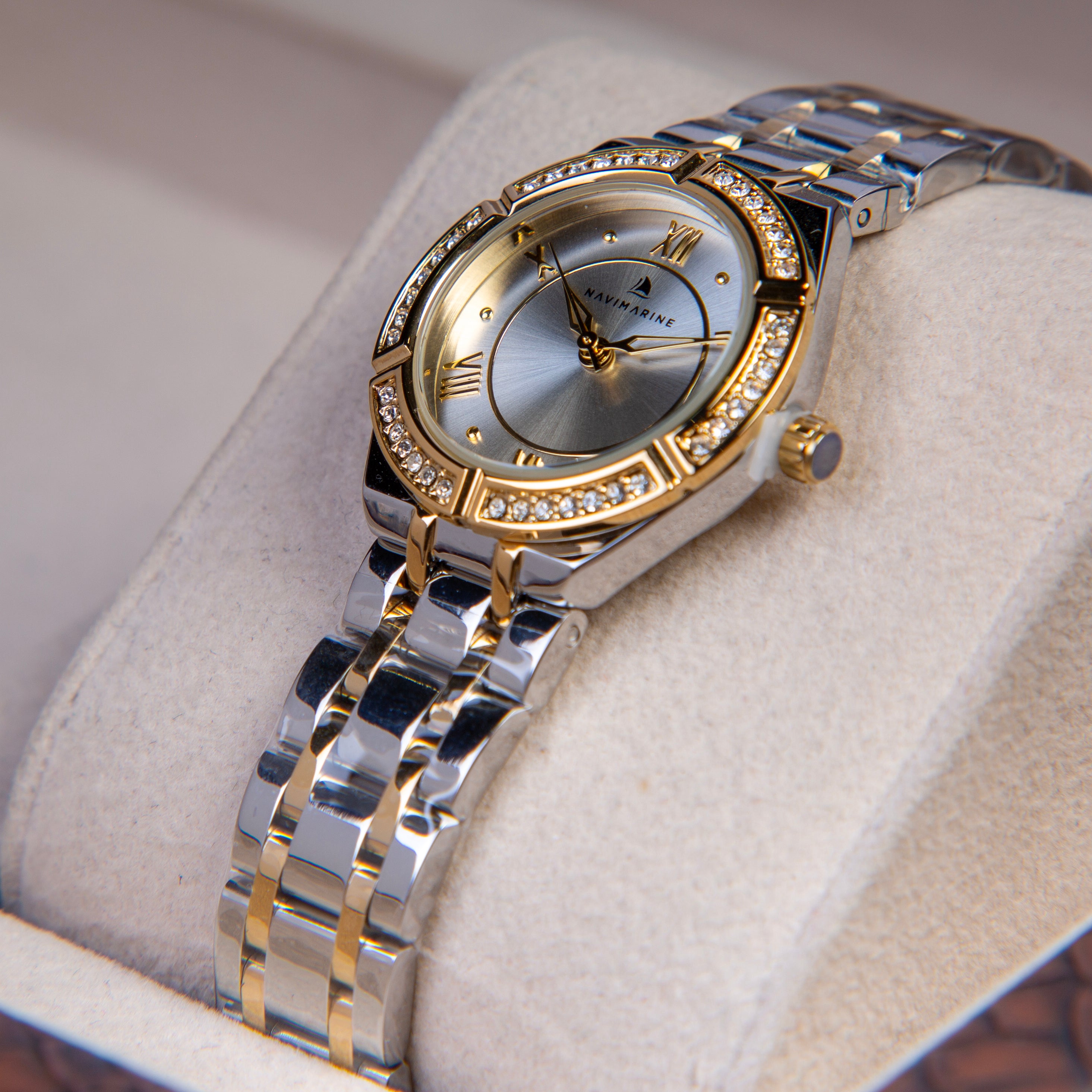 Silver and gold watch with gemstone accents on a light fabric background