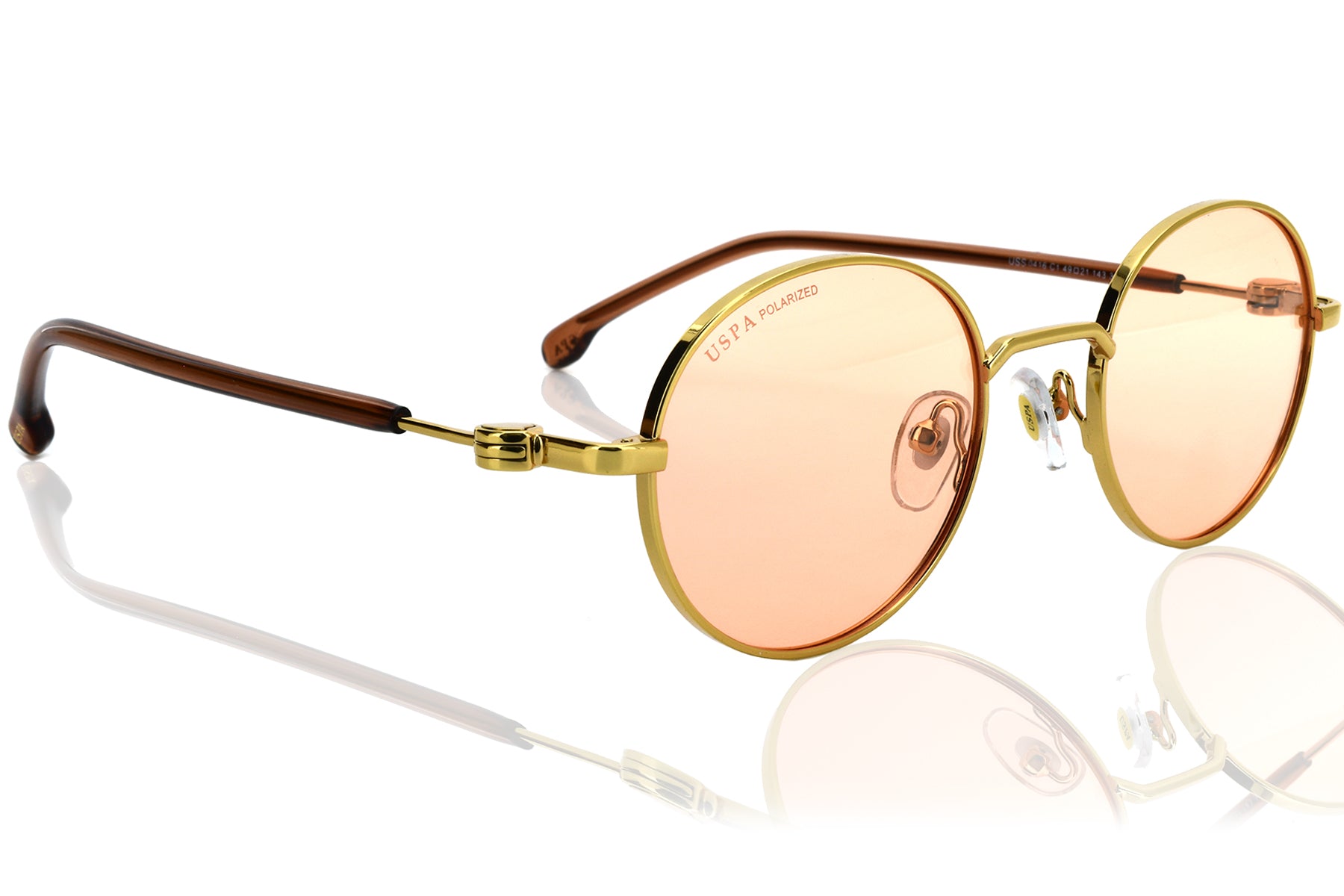 Gold-framed sunglasses with pink-tinted lenses on a white background