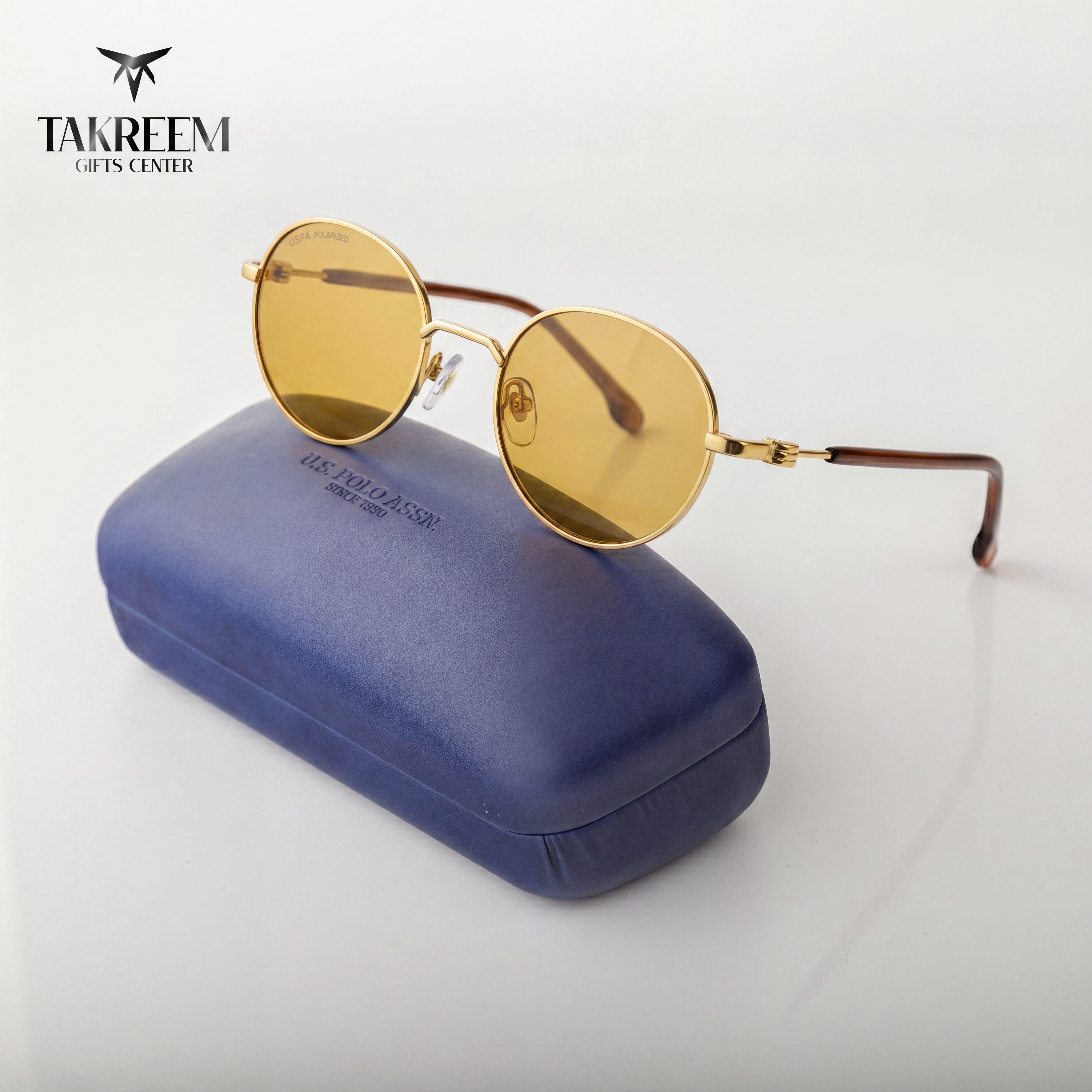 Gold round sunglasses on a blue case with 'Takreem Gifts Center' branding.