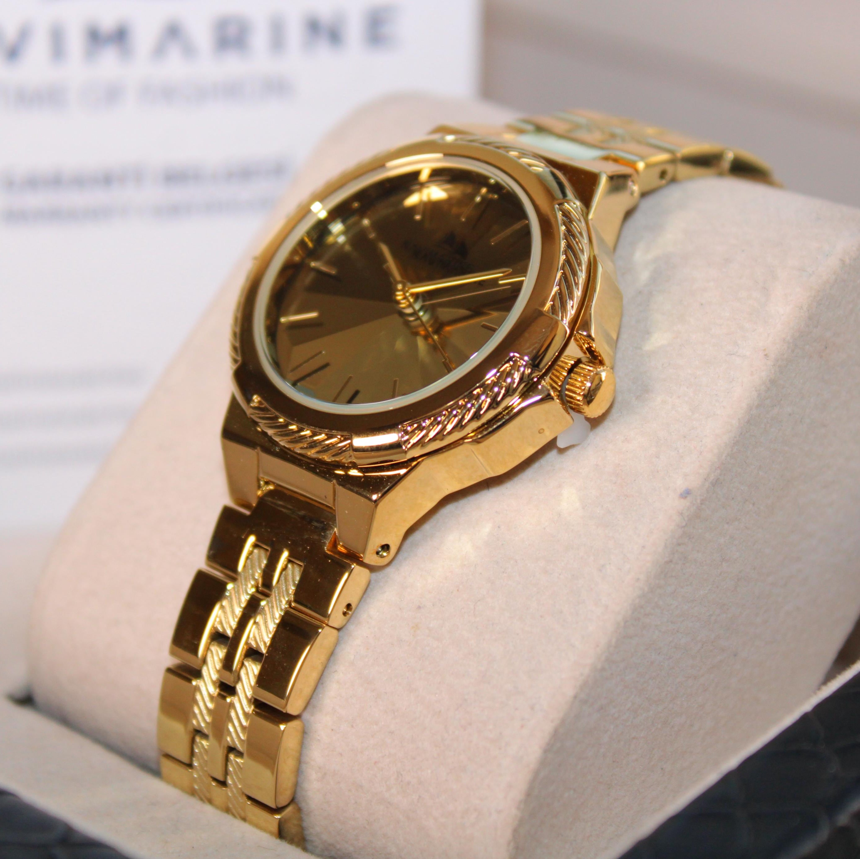 Gold wristwatch on a white cushion with a blurred background