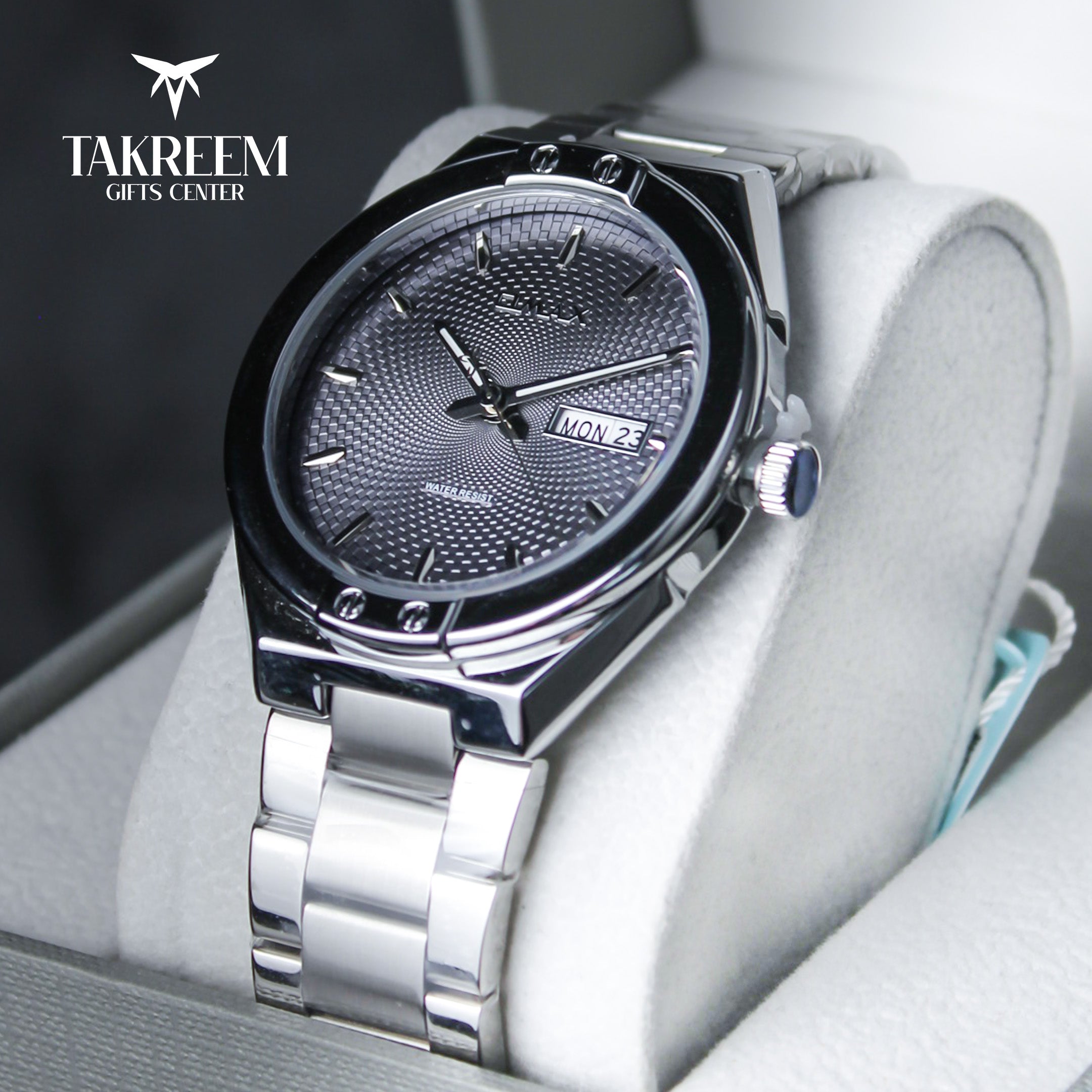 Silver wristwatch with detailed face on a white cushion, brand 'Takreem' visible