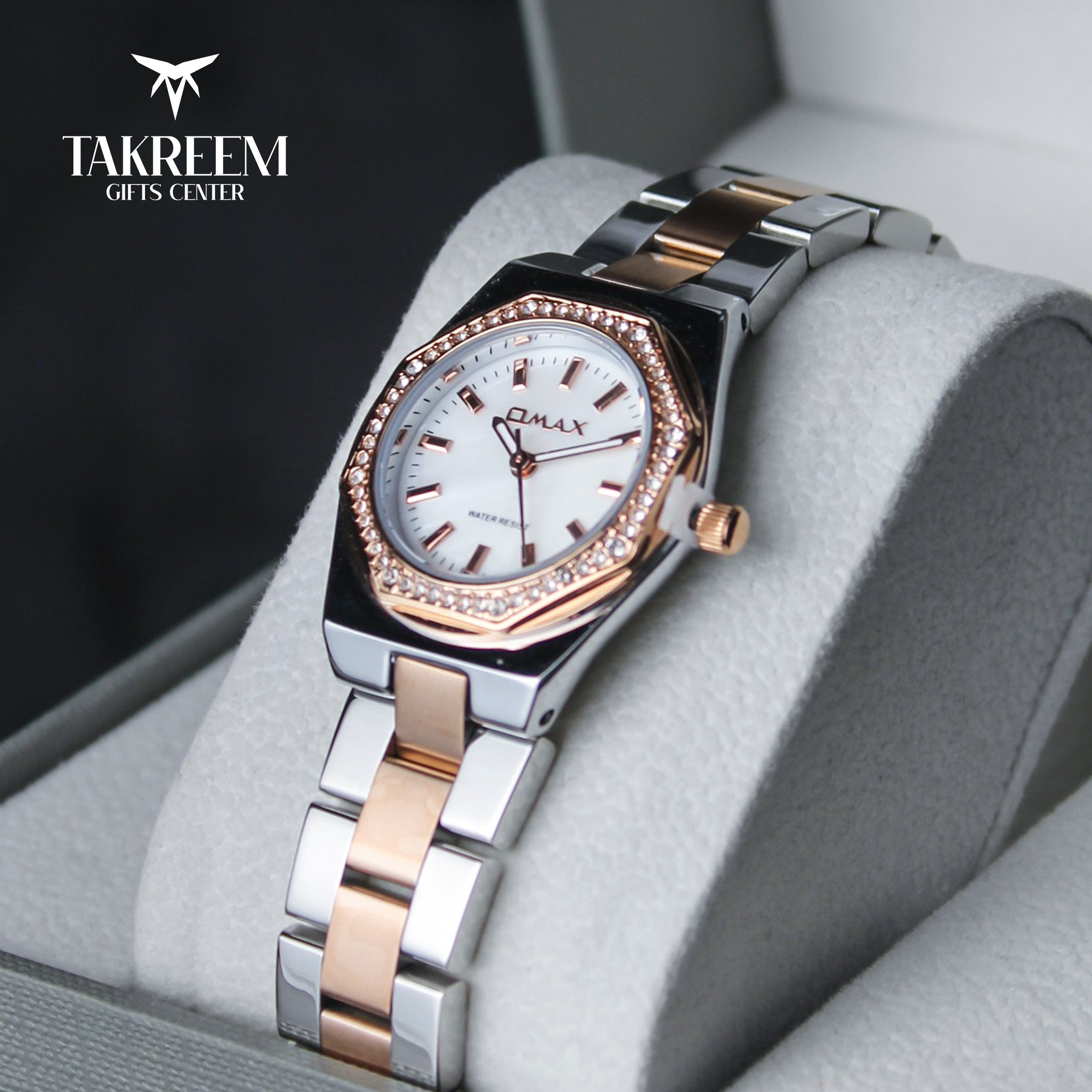 Luxury watch with silver and rose gold band on a gray cushion, brand 'Takreem' visible.