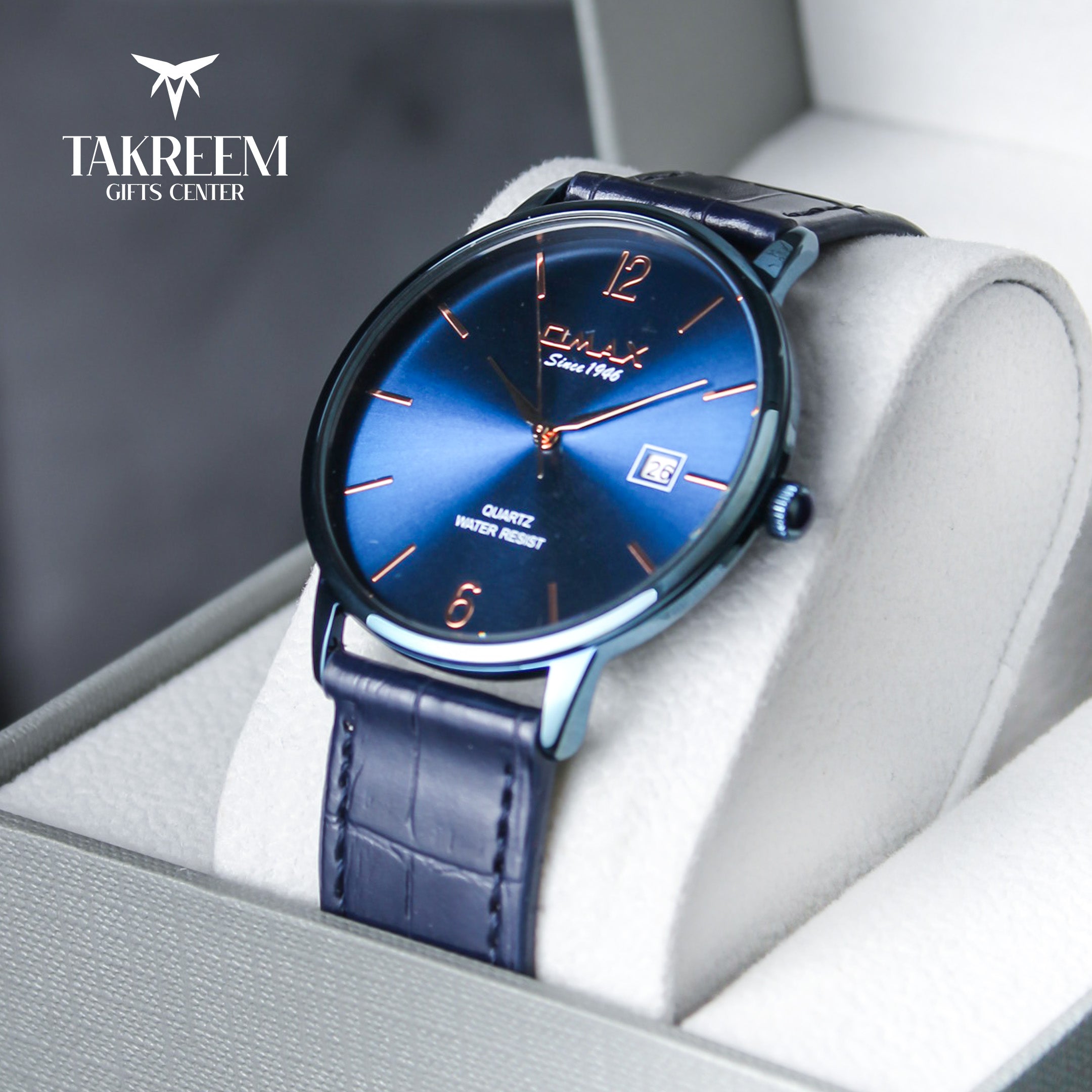 Blue wristwatch with a dark strap in a box, branded 'Takreem Gifts Center'.