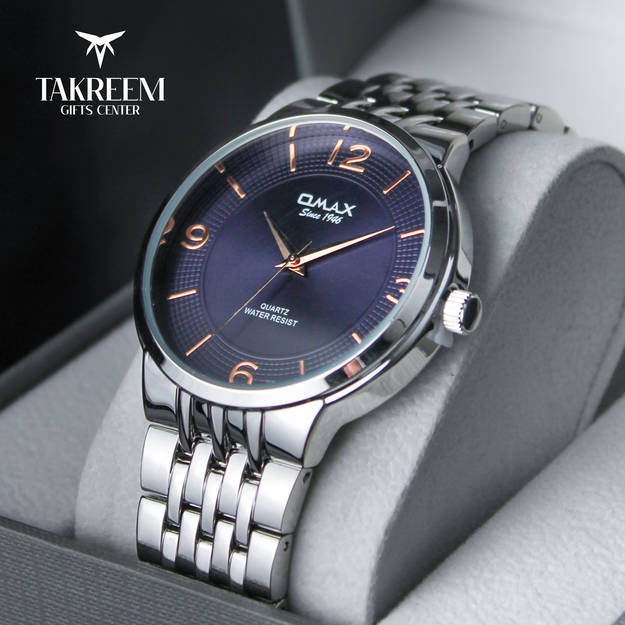 Silver watch with blue dial in a box, branded 'Takreem Gifts Center'.