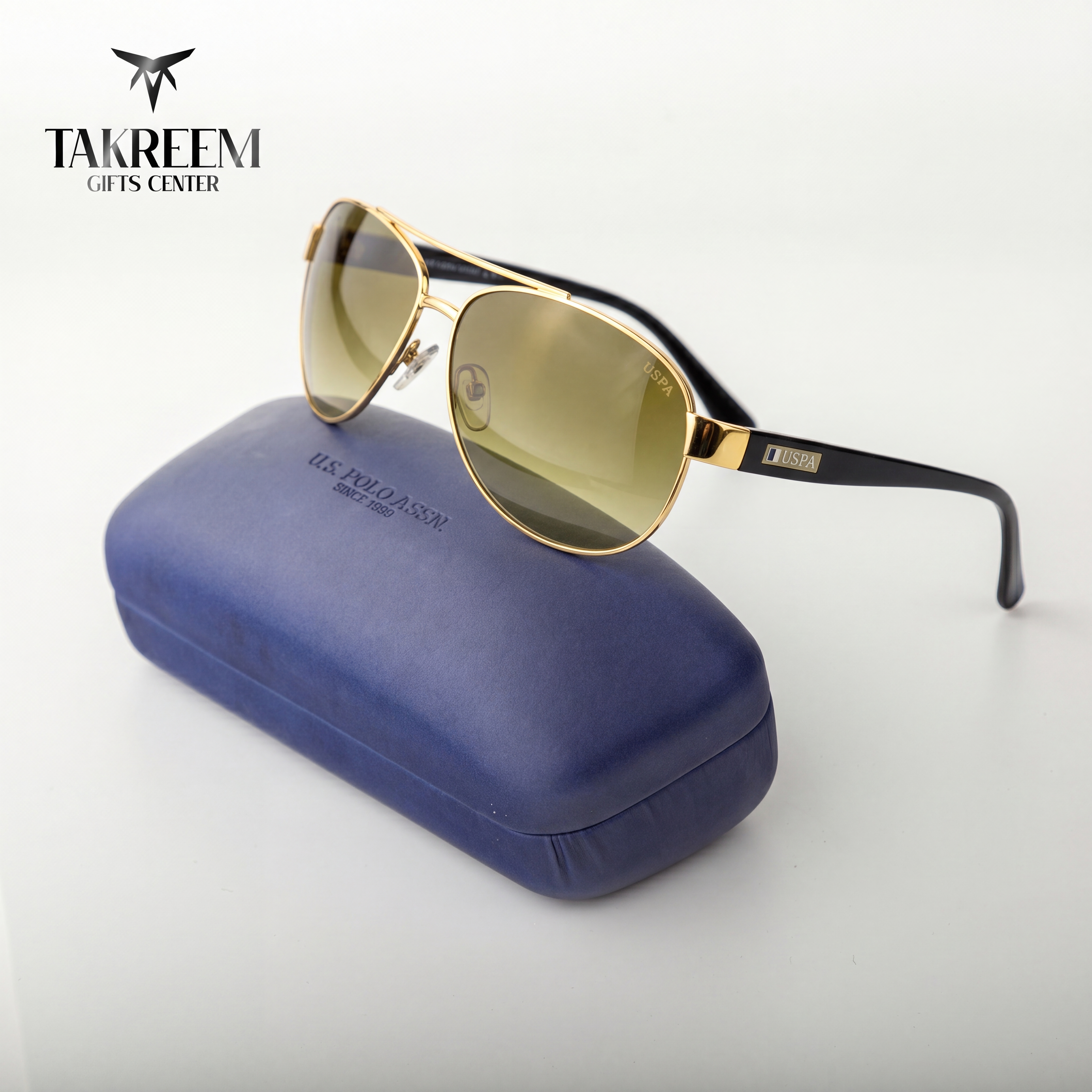 Gold sunglasses with black frames on a blue case, branded 'Takreem Gifts Center'.