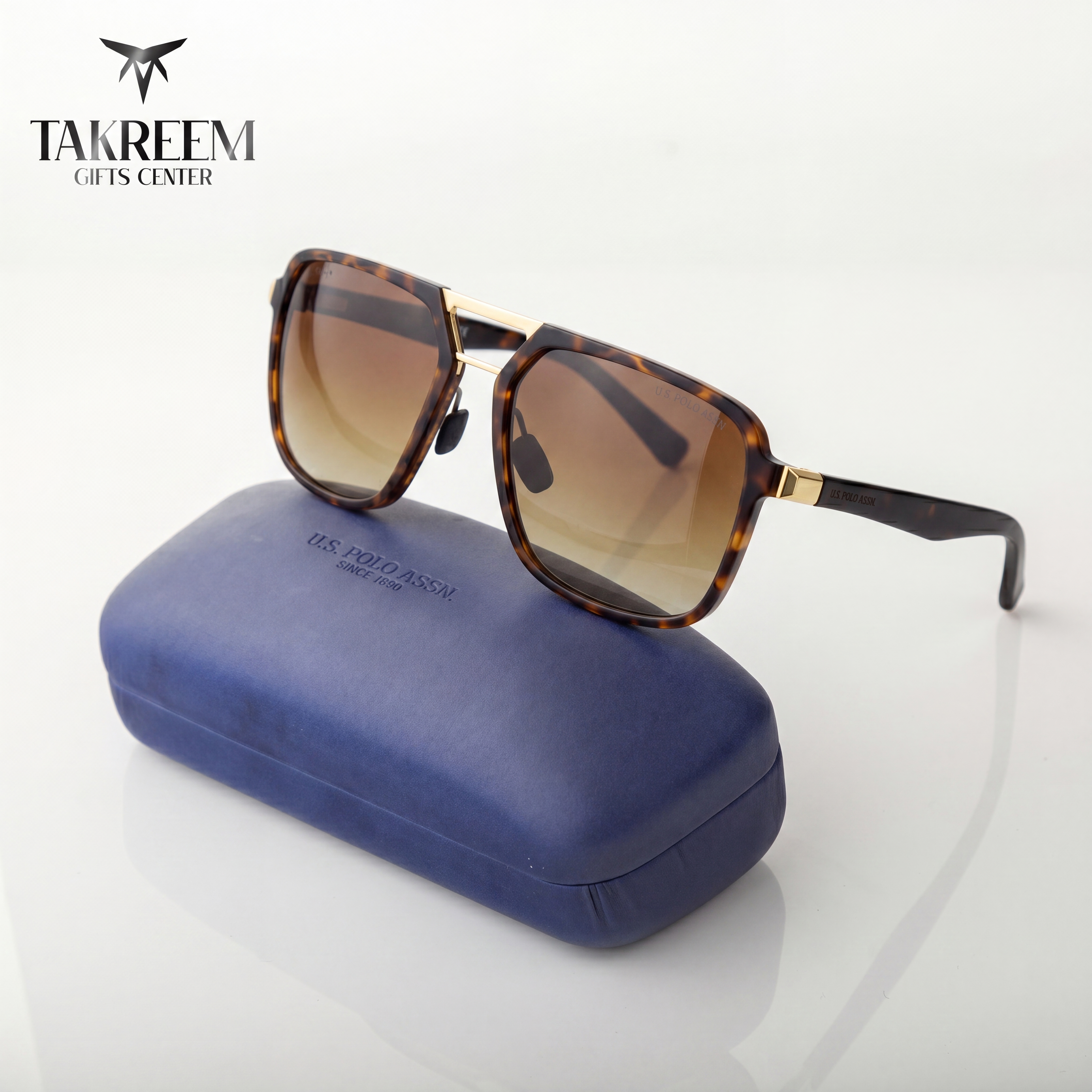 Sunglasses with tortoiseshell frame and brown lenses on a blue case, brand 'Takreem' visible.