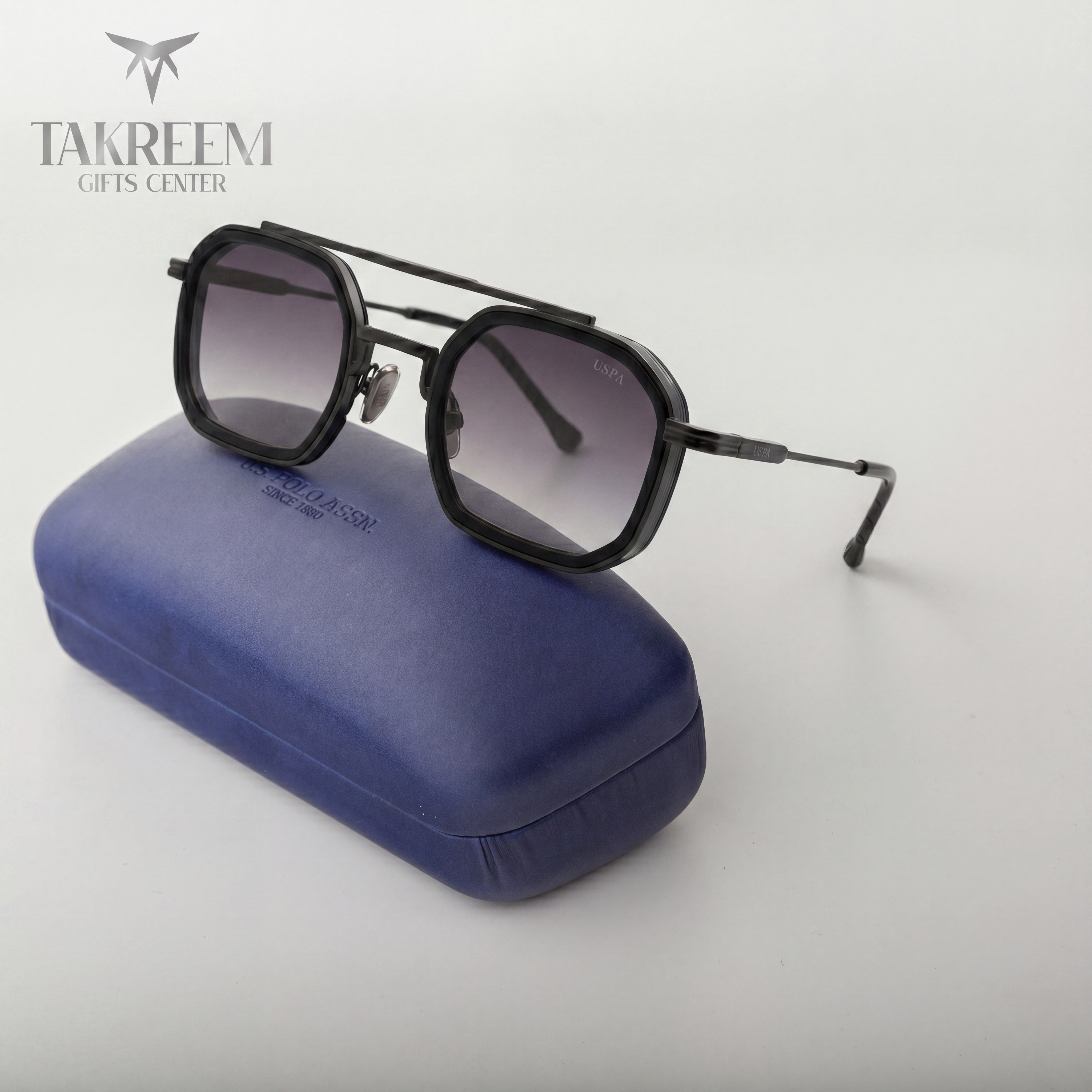 Black sunglasses with gradient lenses on a blue case, brand 'Takreem' visible.