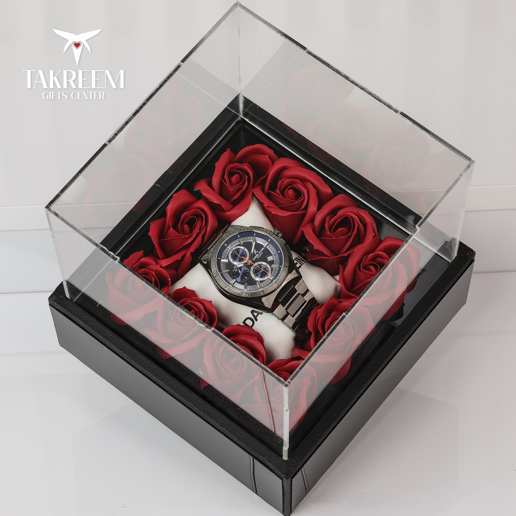 Watch and red roses in a clear box with 'Takreem' branding.