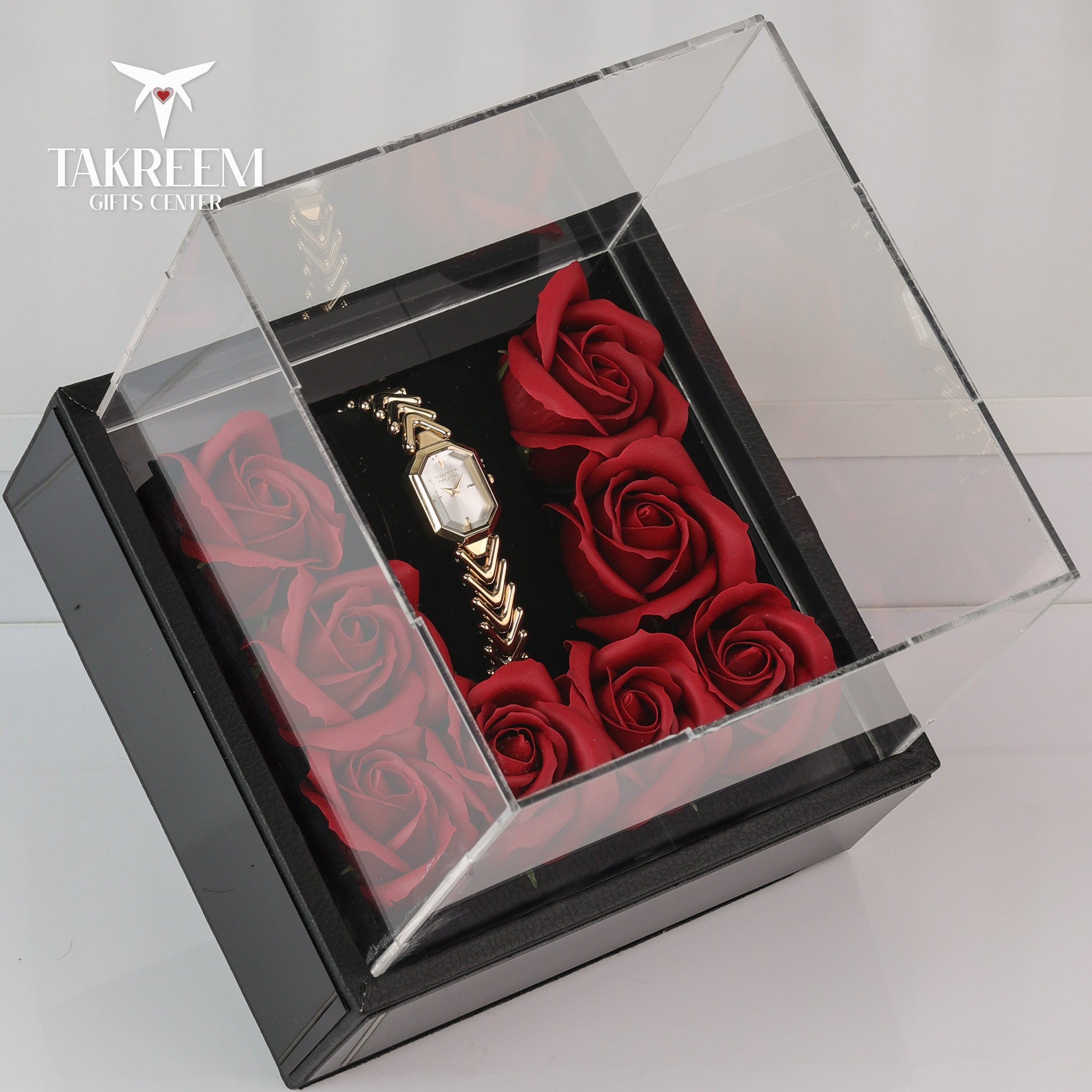 Watch and red roses in a clear box with 'Takreem Gifts Center' branding.