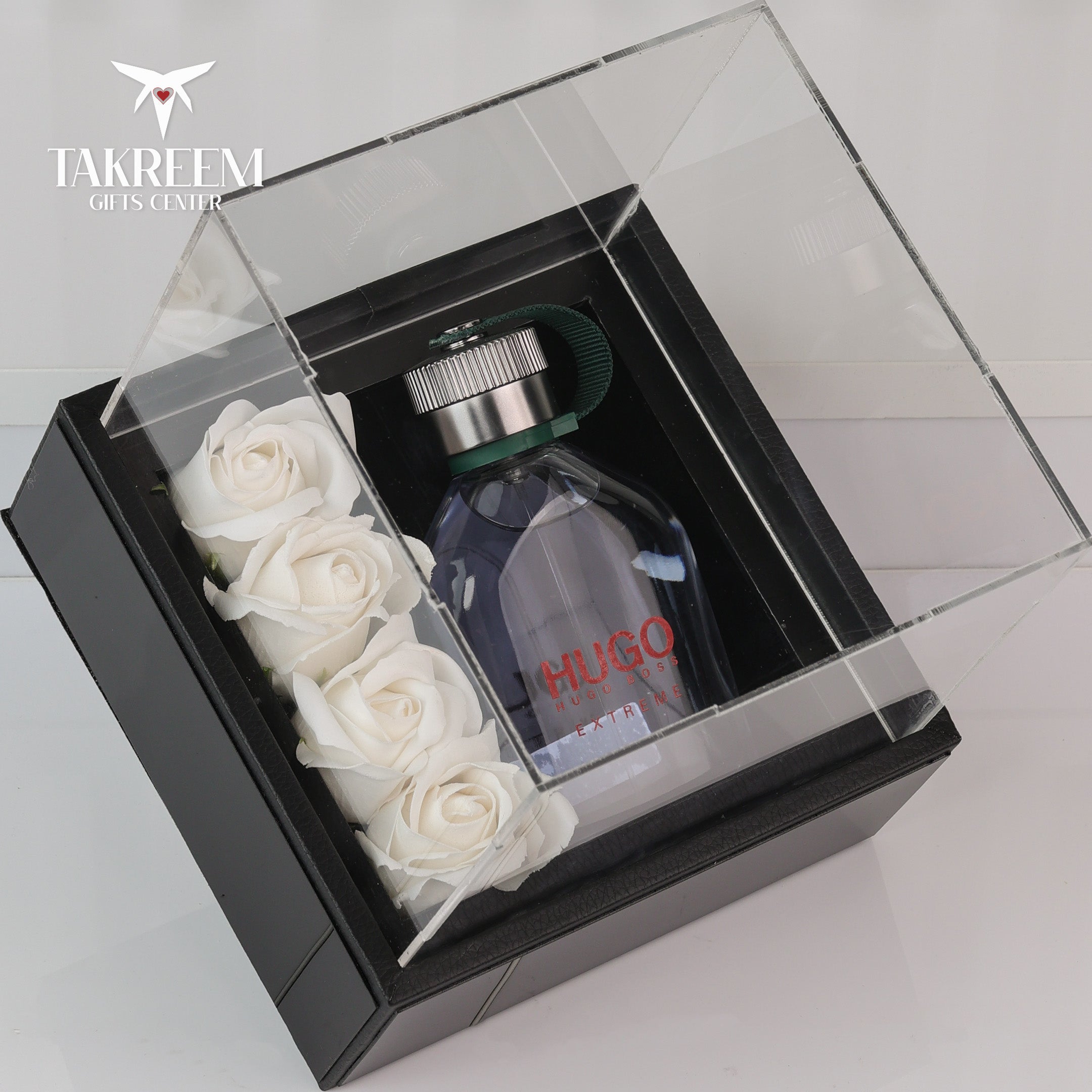 Hugo Boss perfume bottle with white roses in a clear box, branded 'Takreem Gifts Center'.