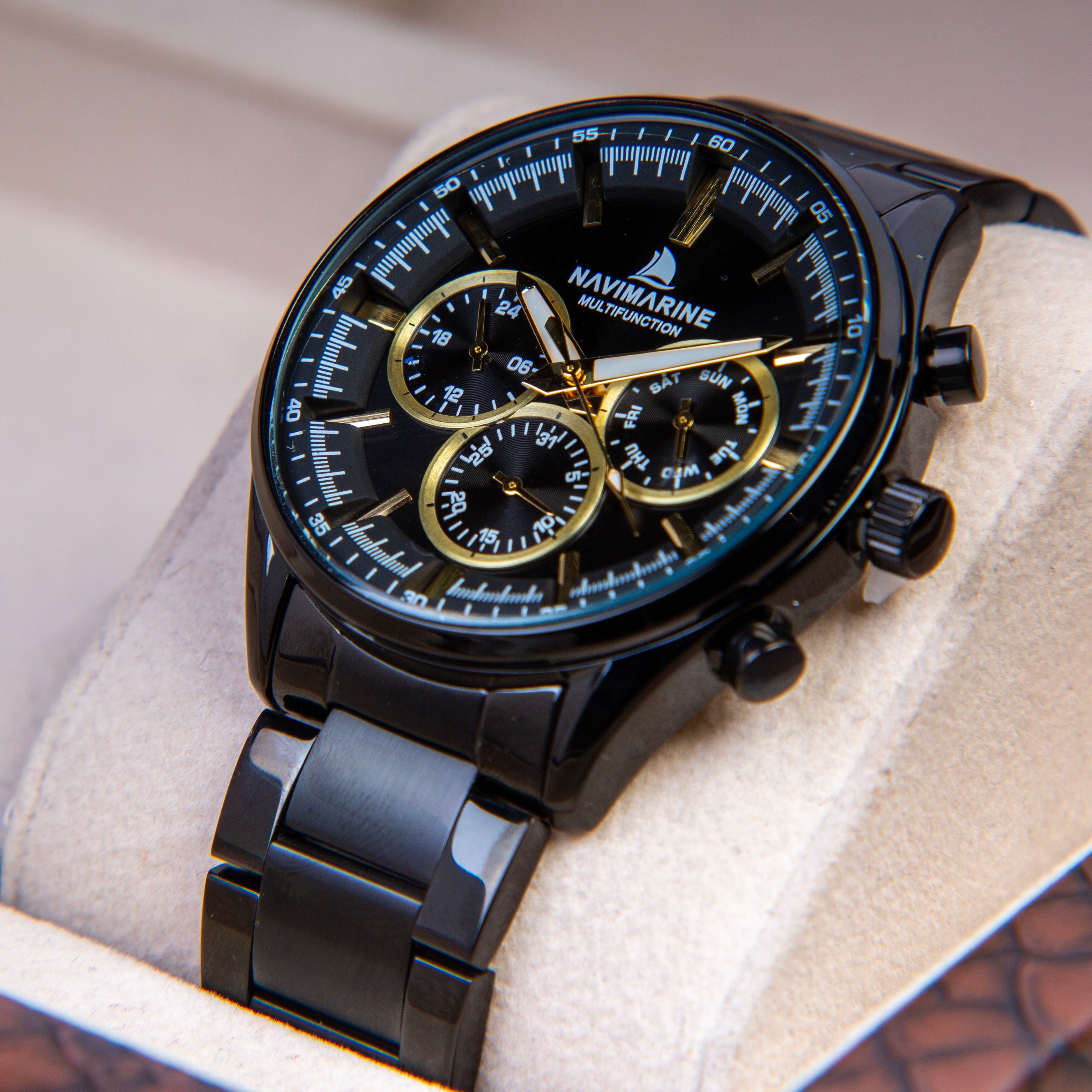 Black and gold Navimarine watch on a white cushion