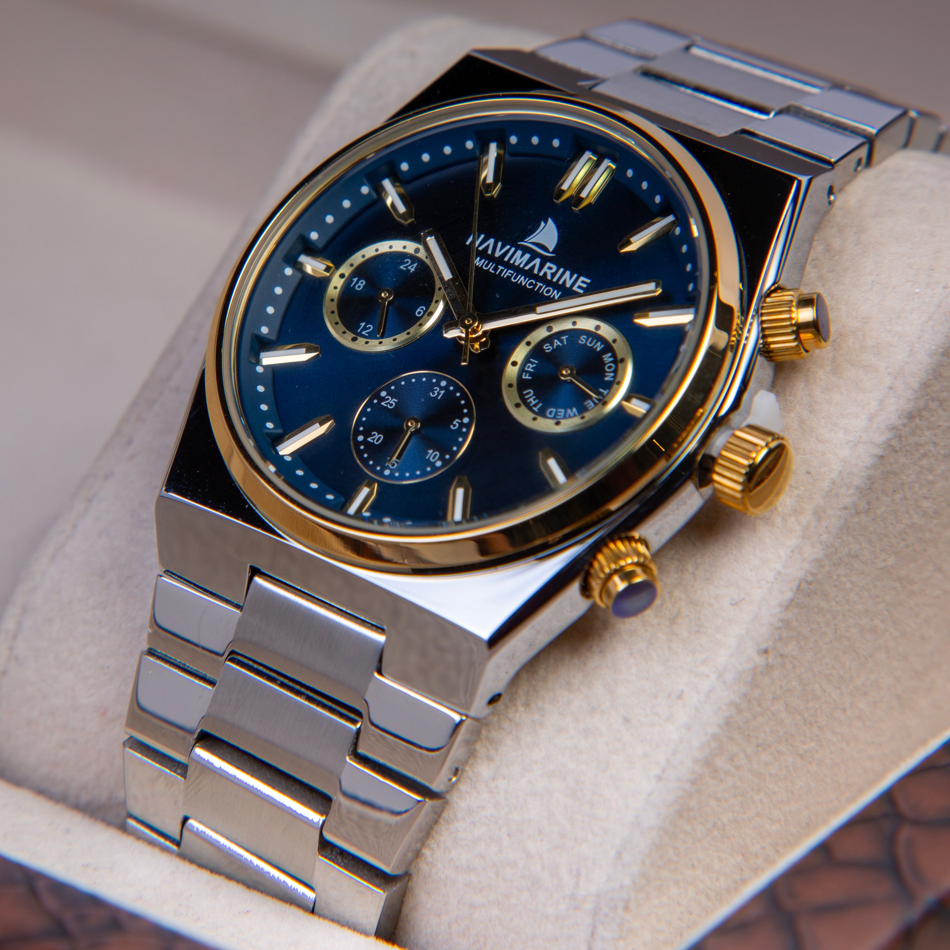 Luxury watch with blue dial and silver and gold accents on a white cushion