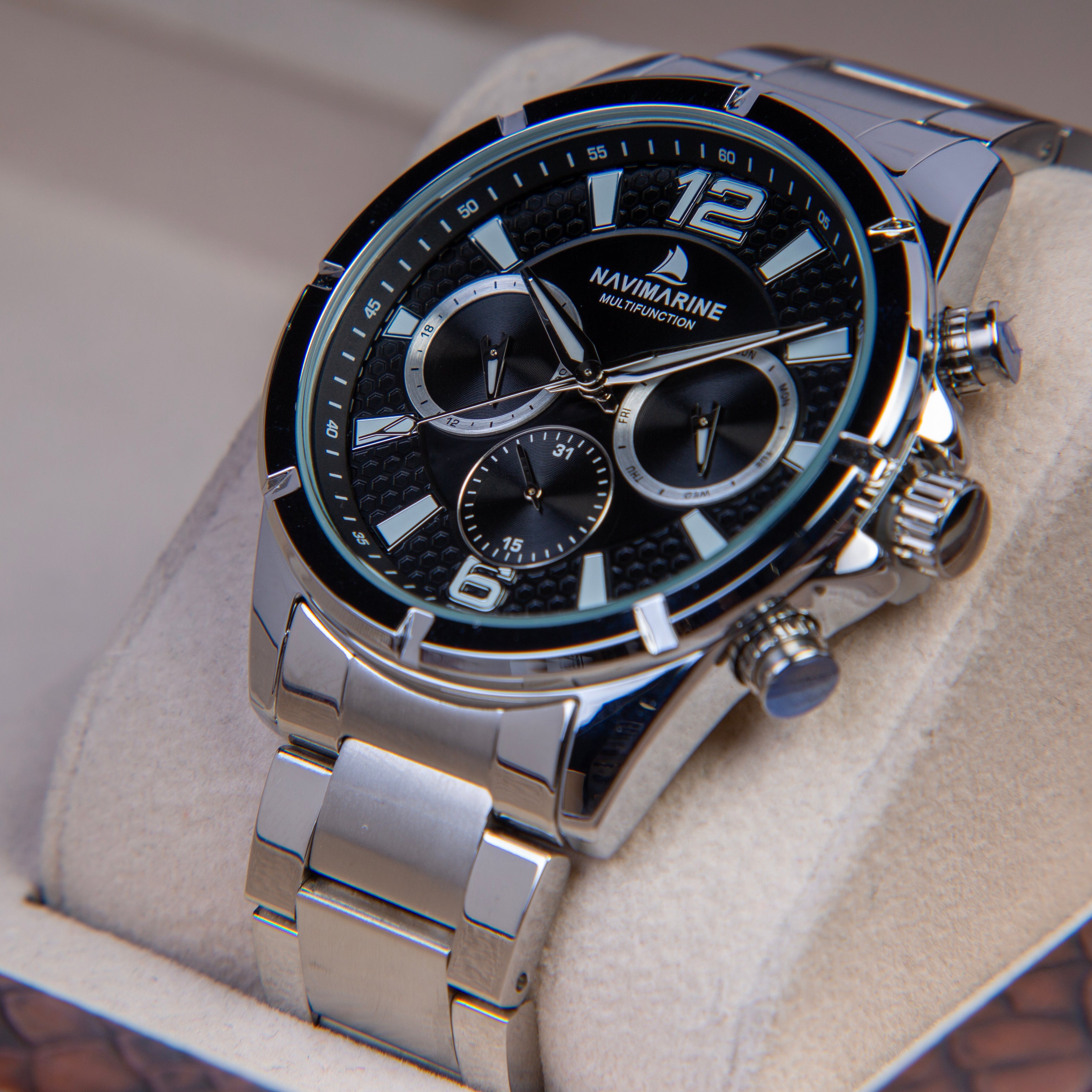 Silver Navimarine watch with black face on a light brown background