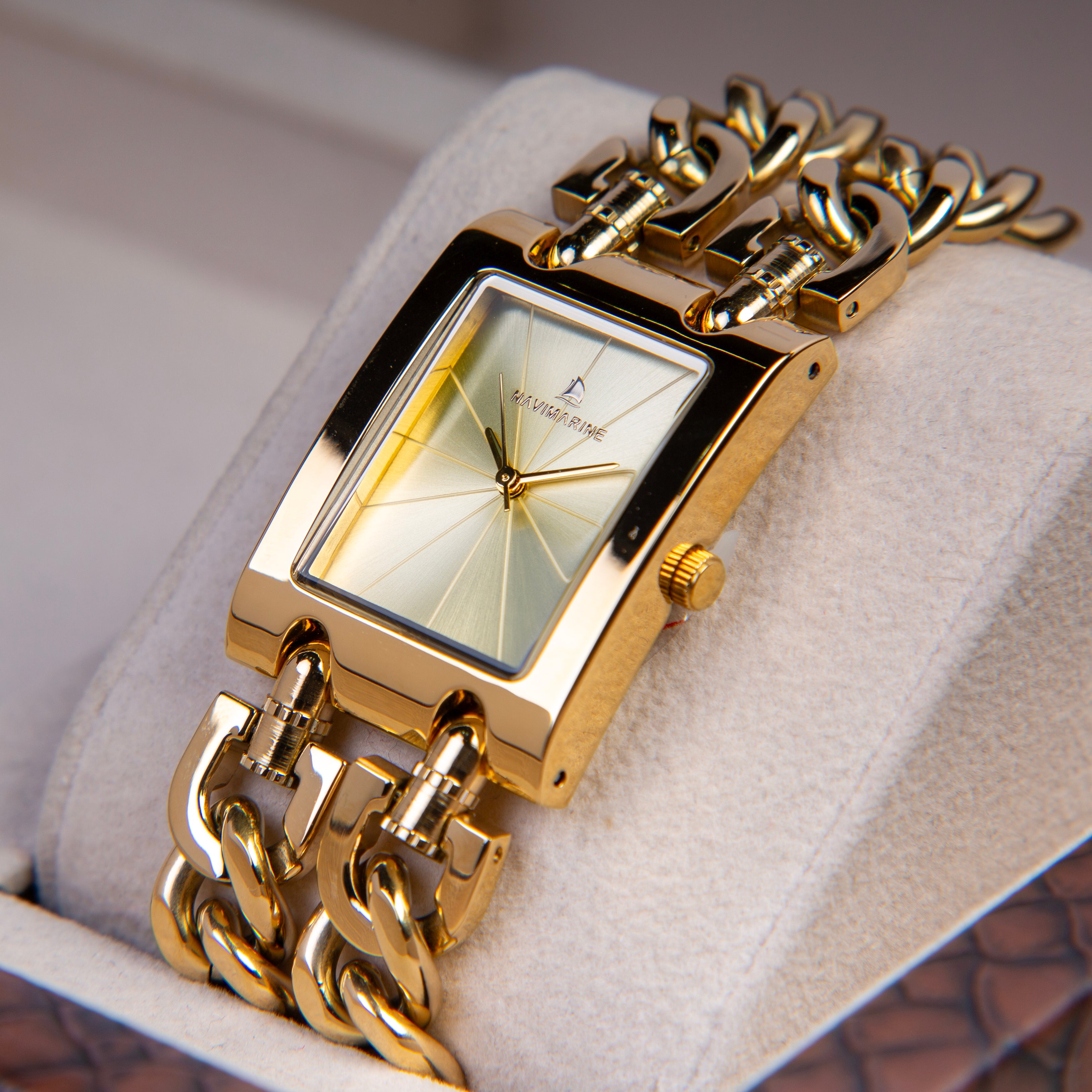 Gold wristwatch with chain strap on a soft surface