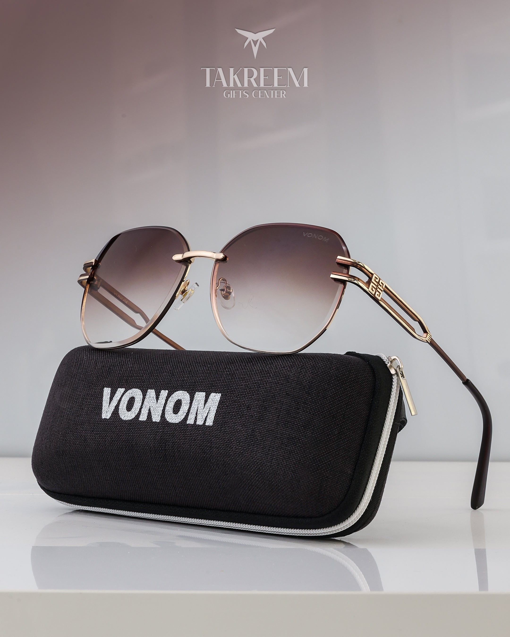 Sunglasses with gold frame and gradient lenses on a black case labeled 'Vonom' with Takreem brand logo in the background.