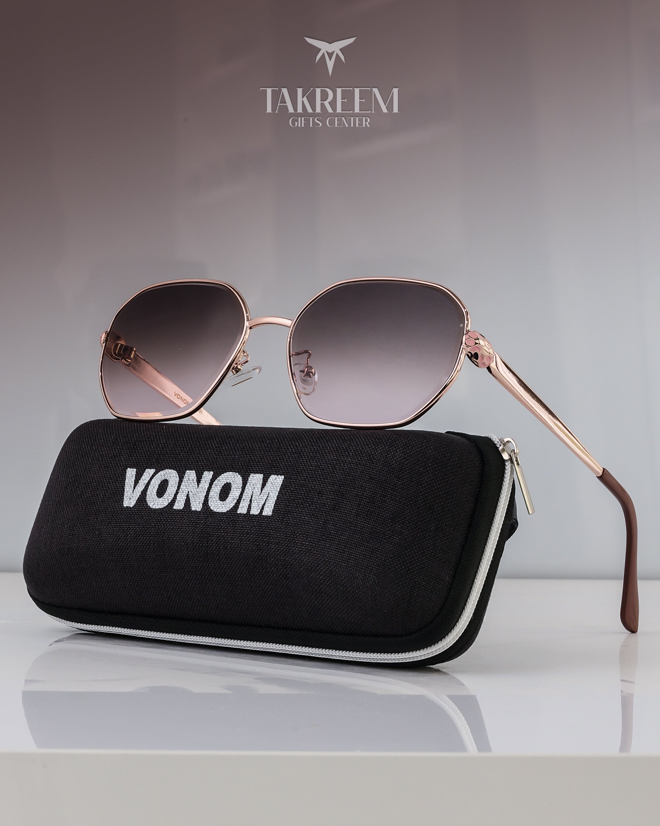 Sunglasses with rose gold frame and gradient lenses on a black case labeled 'VONOM' with 'Takreemi Gifts Center' logo in the background.