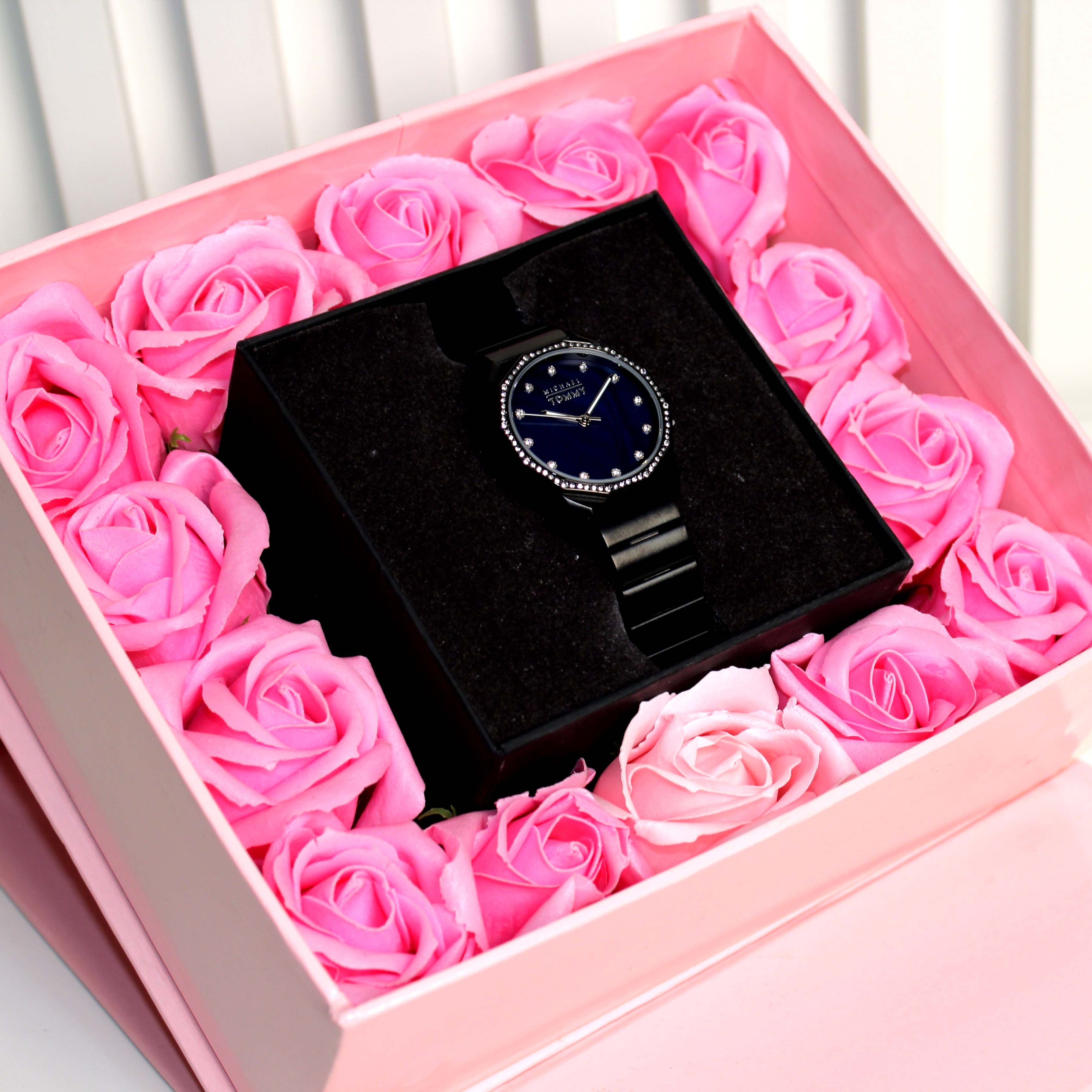 Watch in a box surrounded by pink roses on a white background