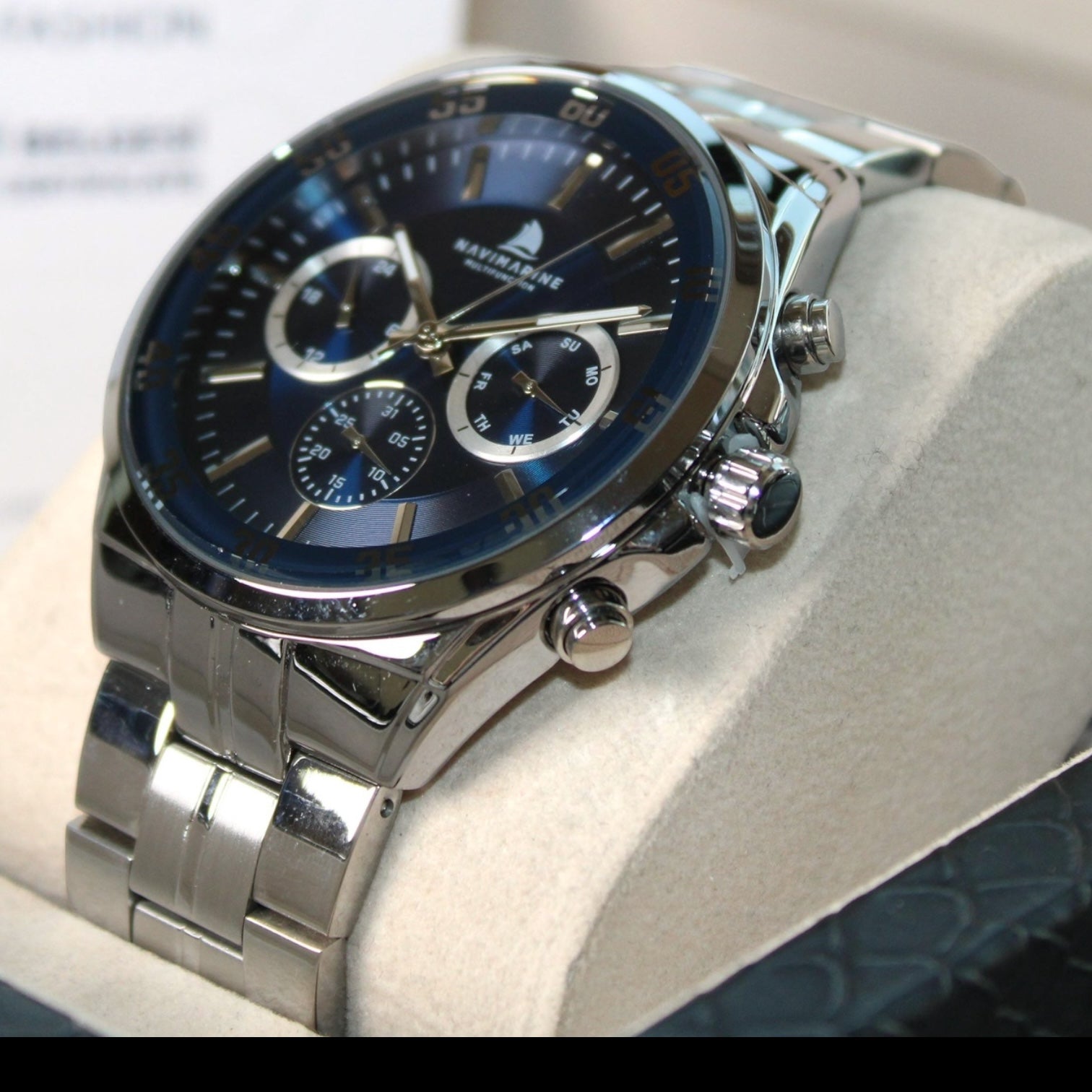 Silver watch with a blue face on a white cushion