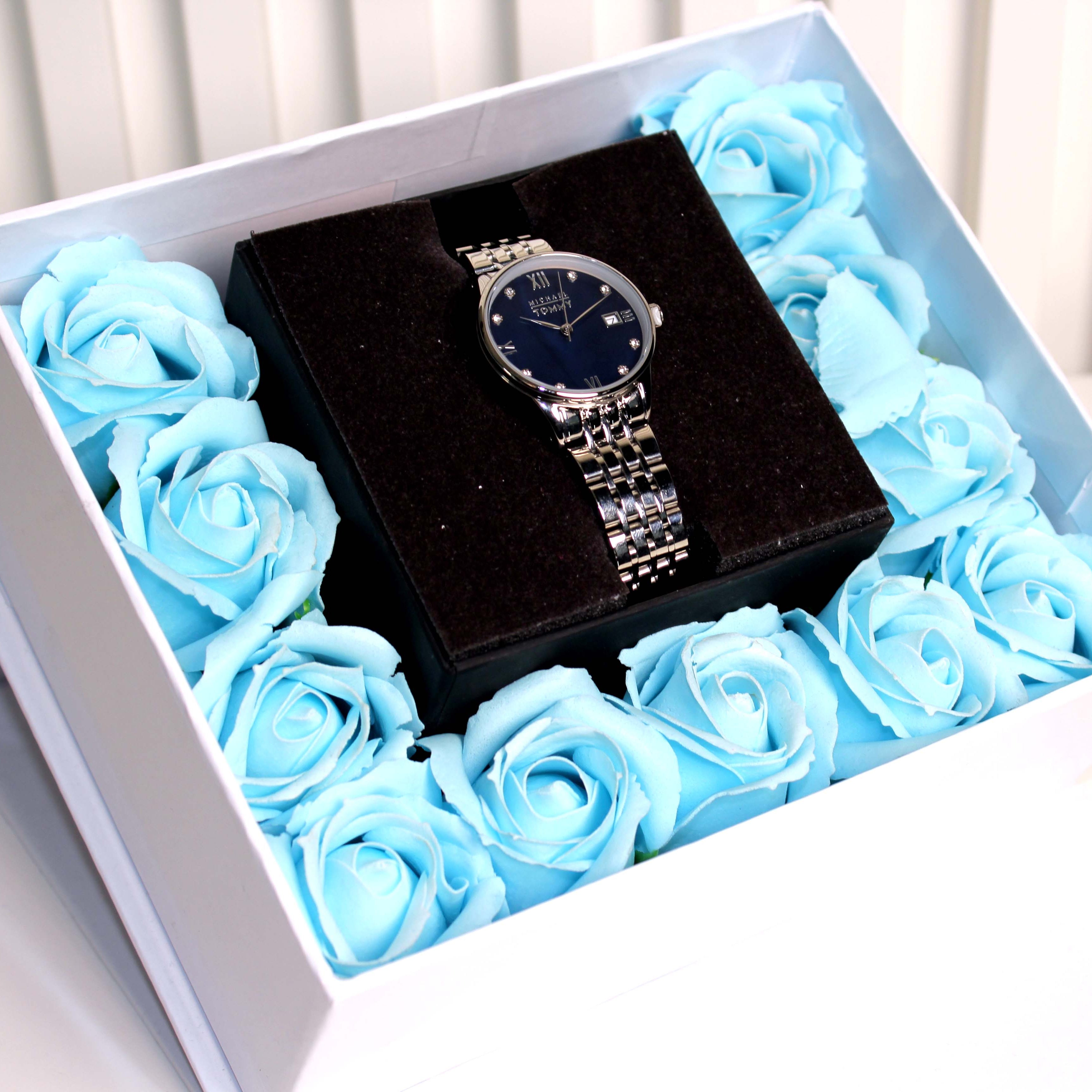 Watch in a box surrounded by blue roses