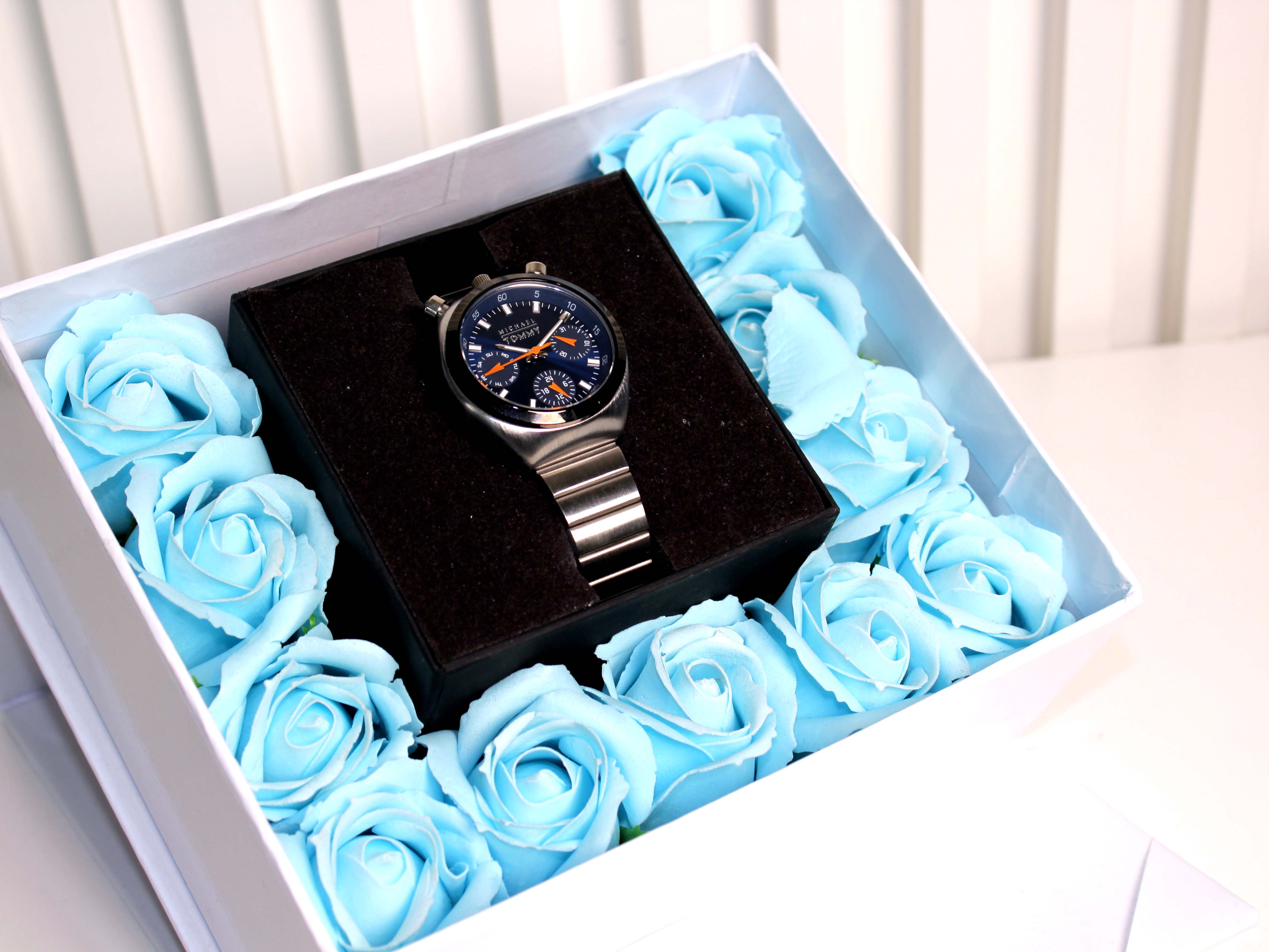 Watch in a box surrounded by blue roses