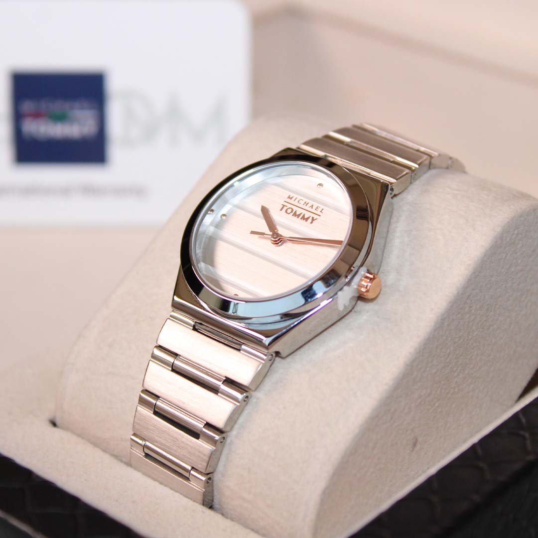 Silver Tommy watch on a white cushion with a blurred background