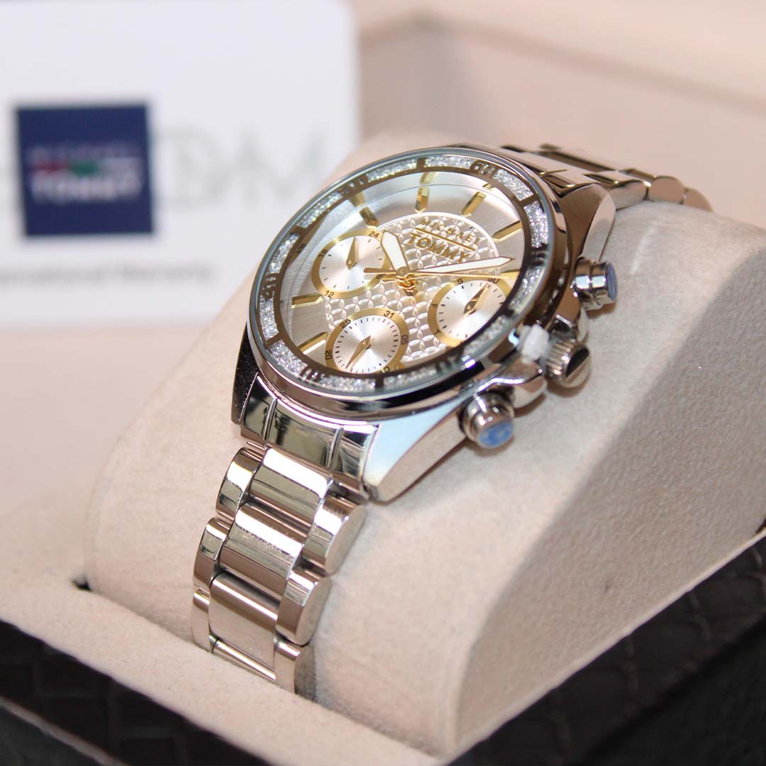 Silver watch with intricate design on a white cushion, brand logo visible in the background