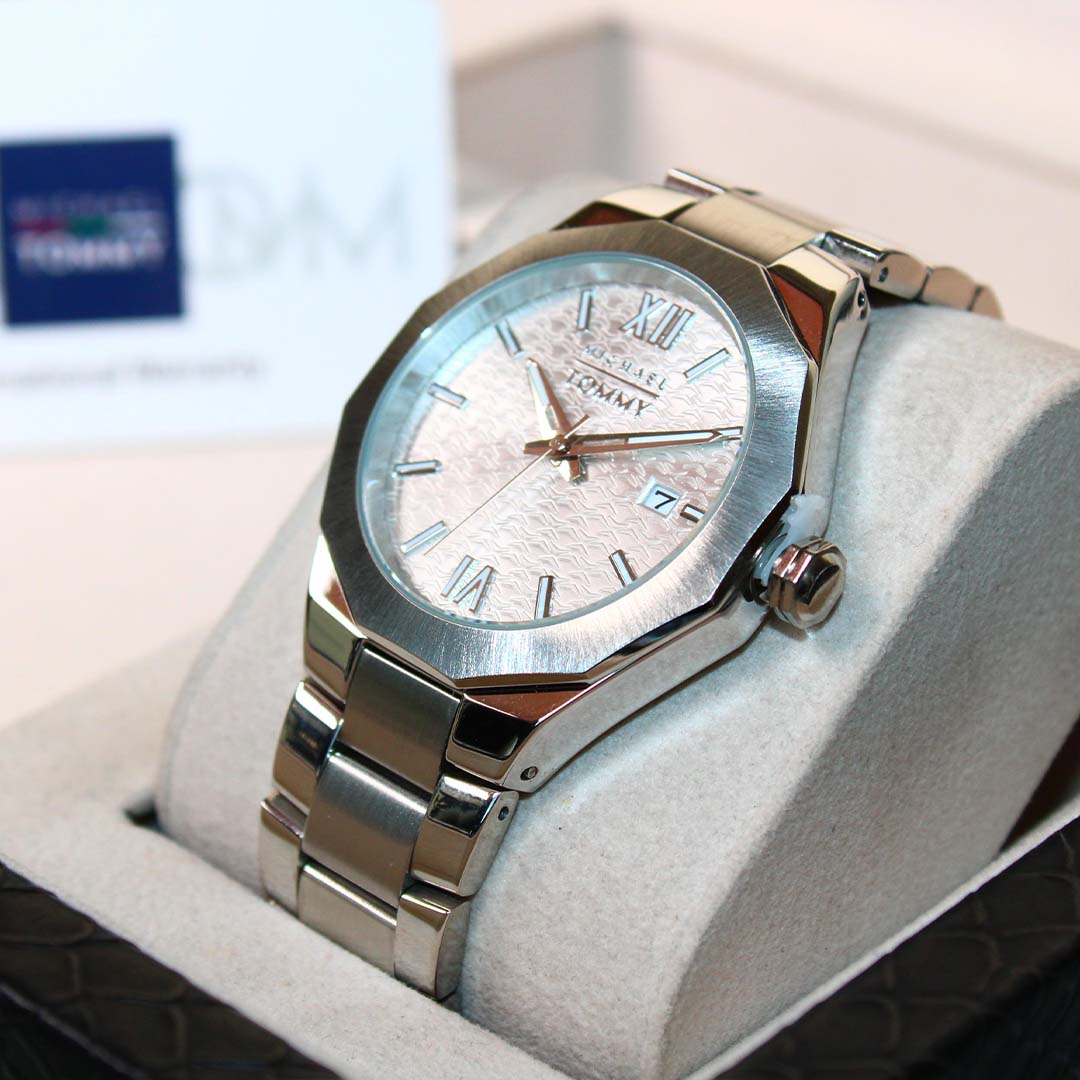 Silver Tommy Hilfiger watch on a white cushion with a blurred background