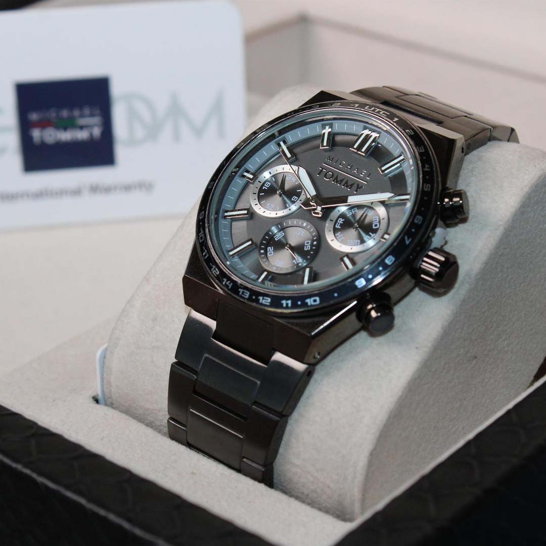 Tommy Hilfiger watch with black strap on a gray cushion, brand name visible