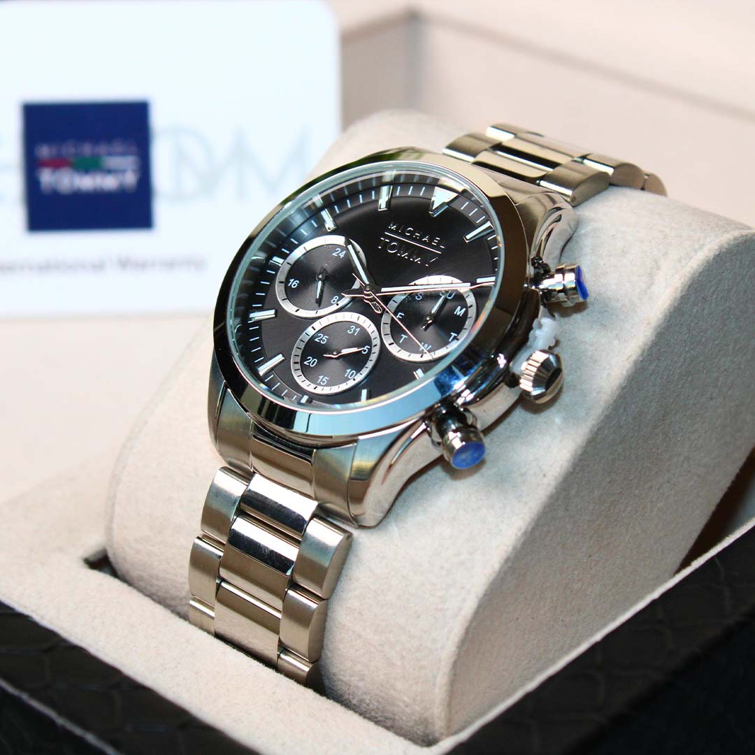 Silver watch with black face on a white cushion, brand logo visible