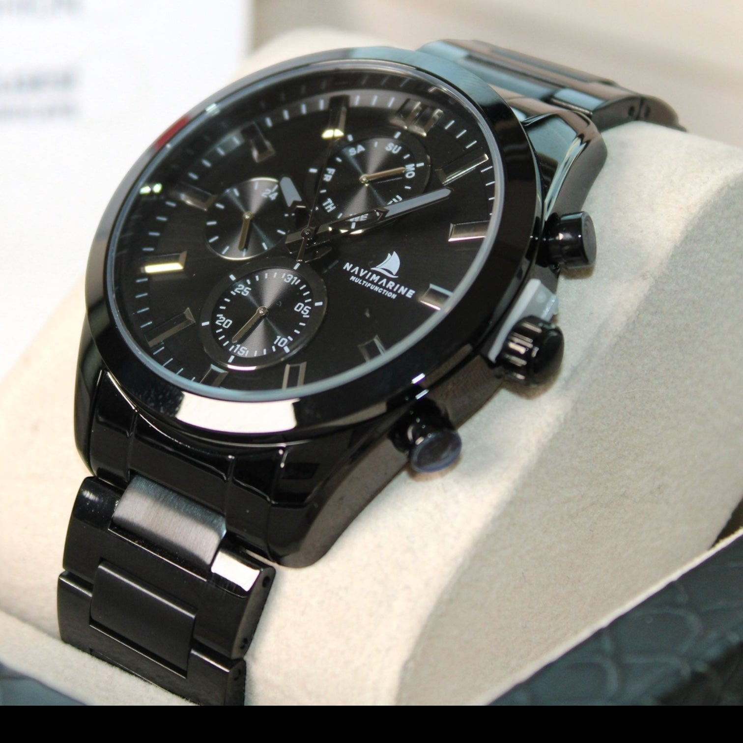 Black wristwatch with detailed face on a white cushion