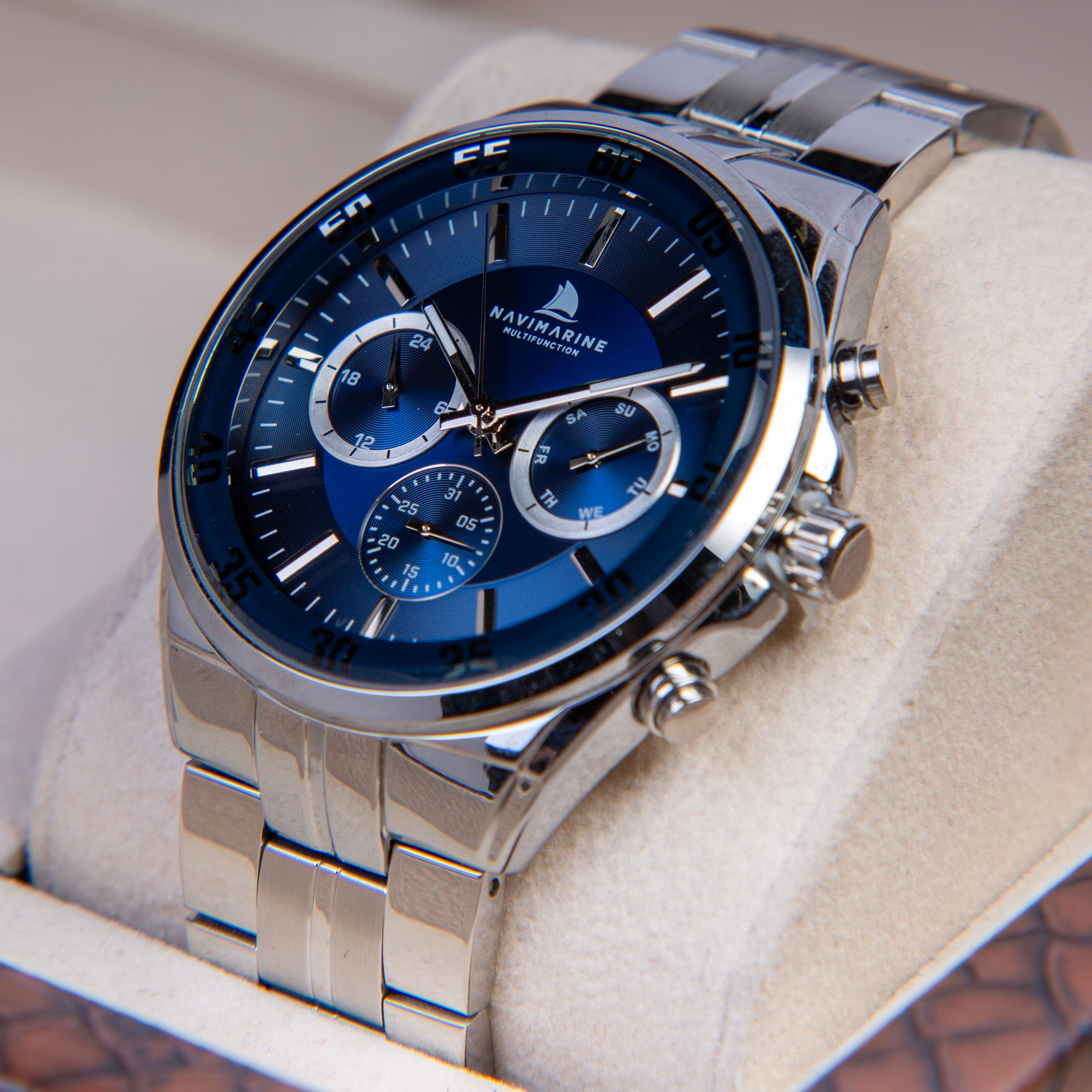 Silver watch with blue face on a white cushion