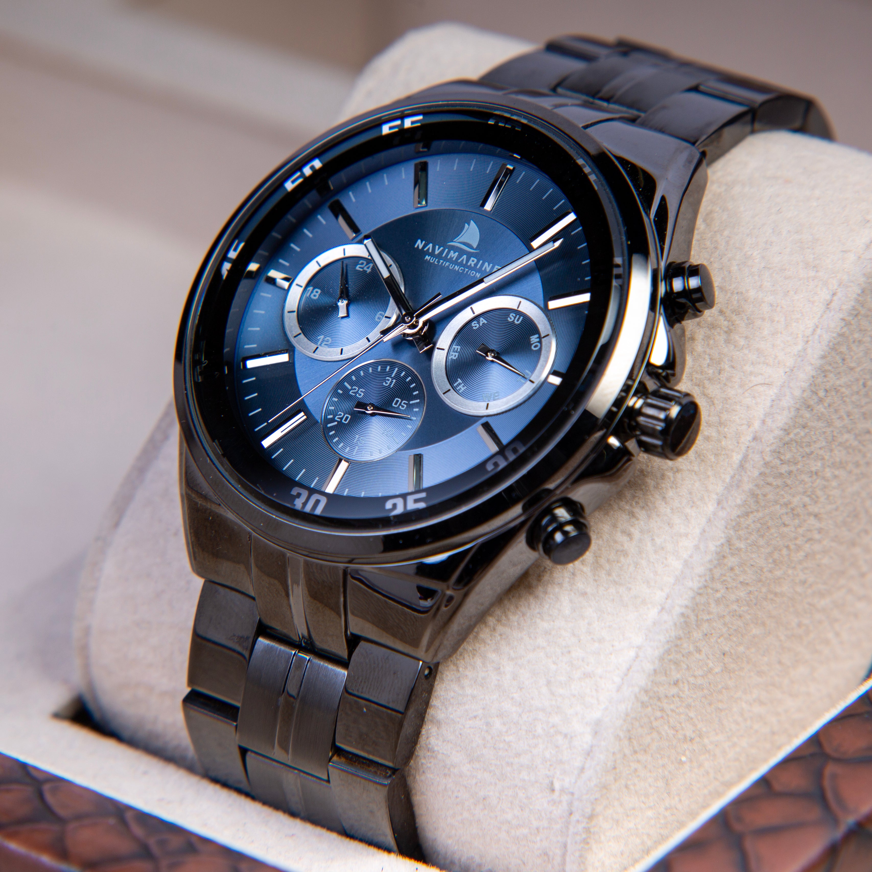 Luxury watch with black metal strap and blue dial on a soft surface