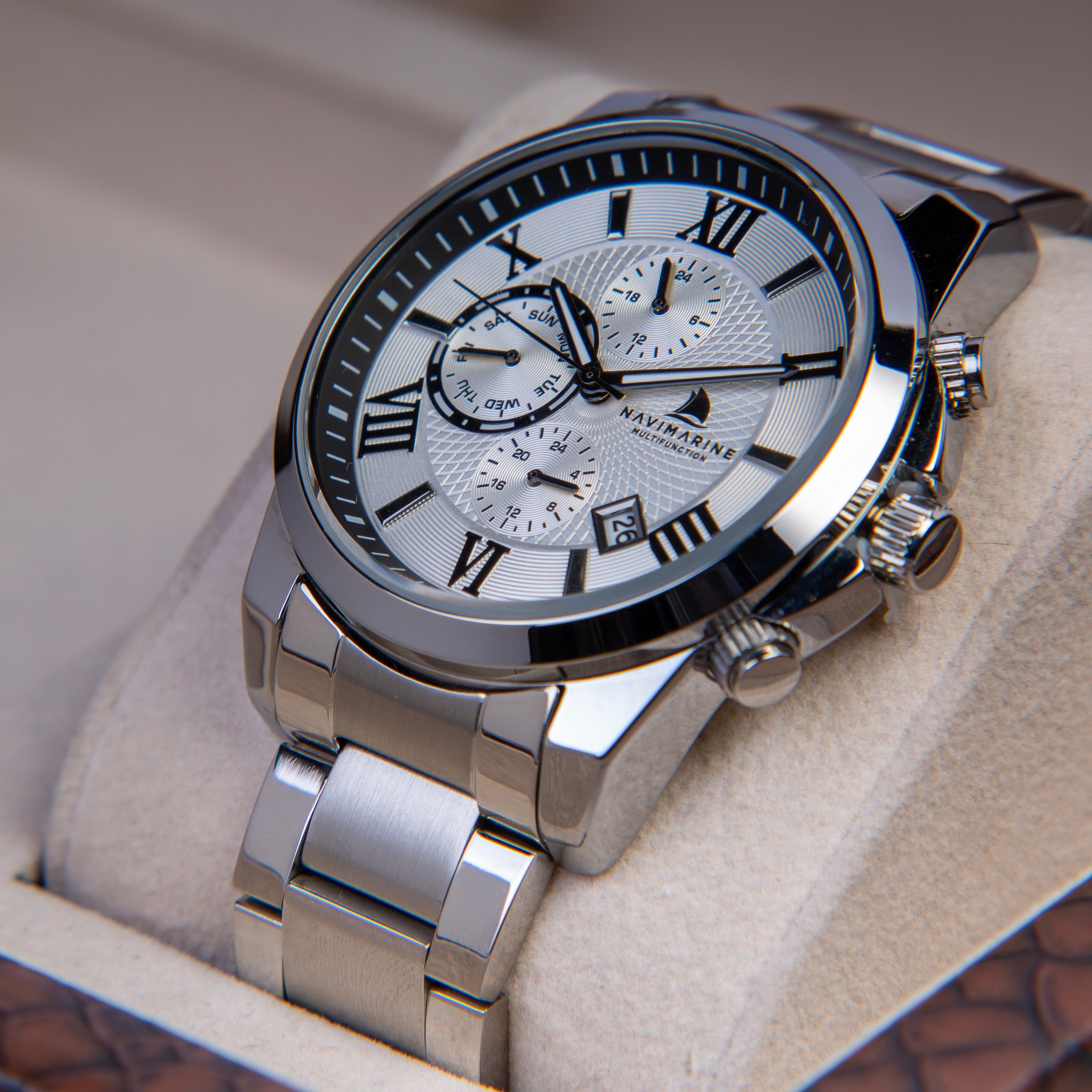 Silver wristwatch with a detailed face on a textured surface