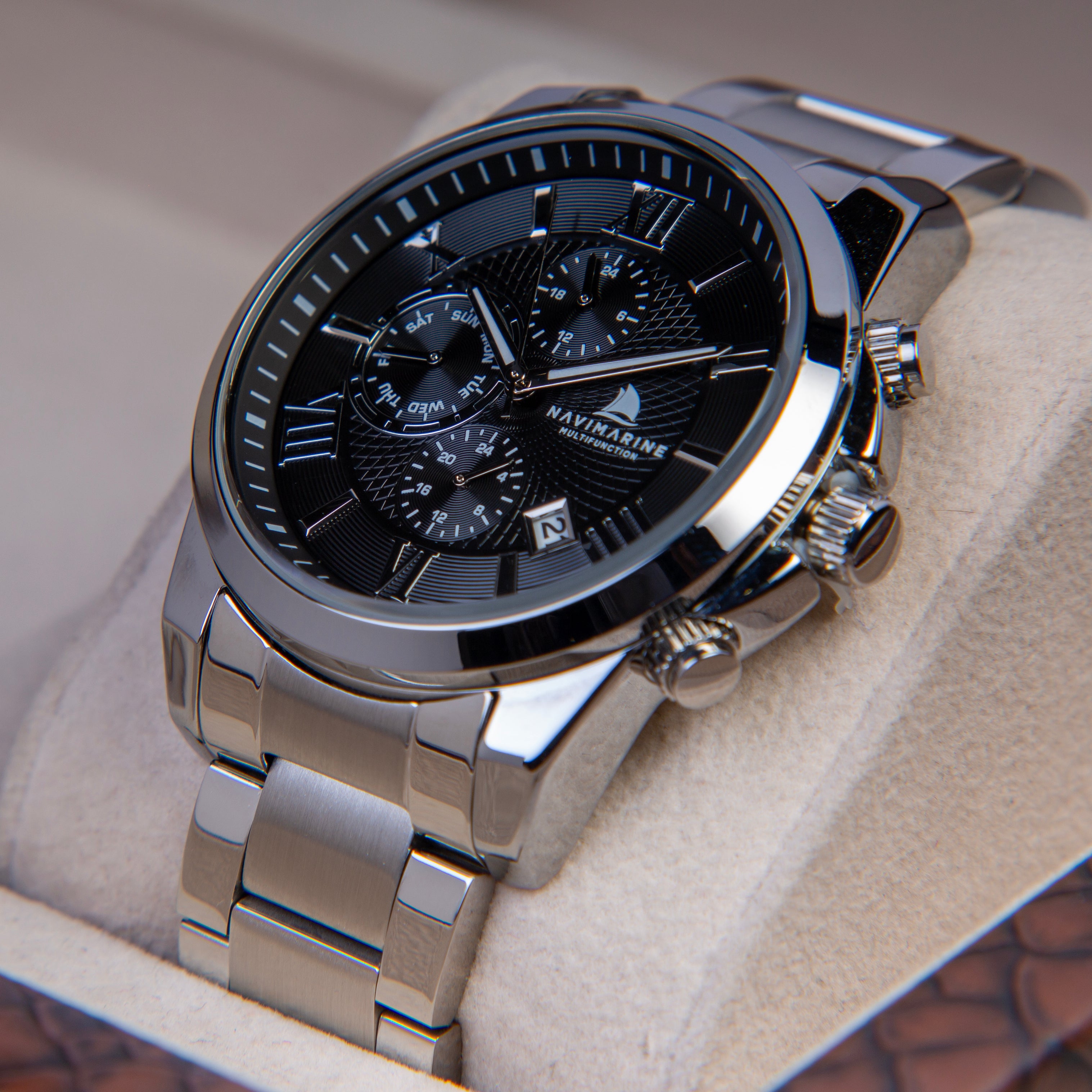 Silver wristwatch with a black face on a beige cushion