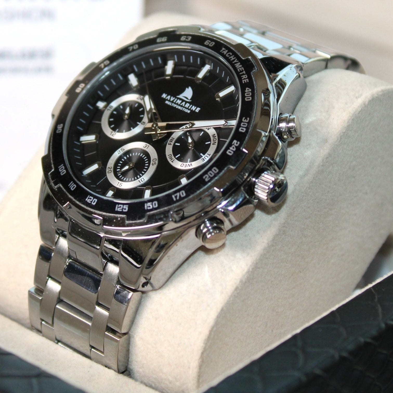 Silver wristwatch with black dial on a white cushion