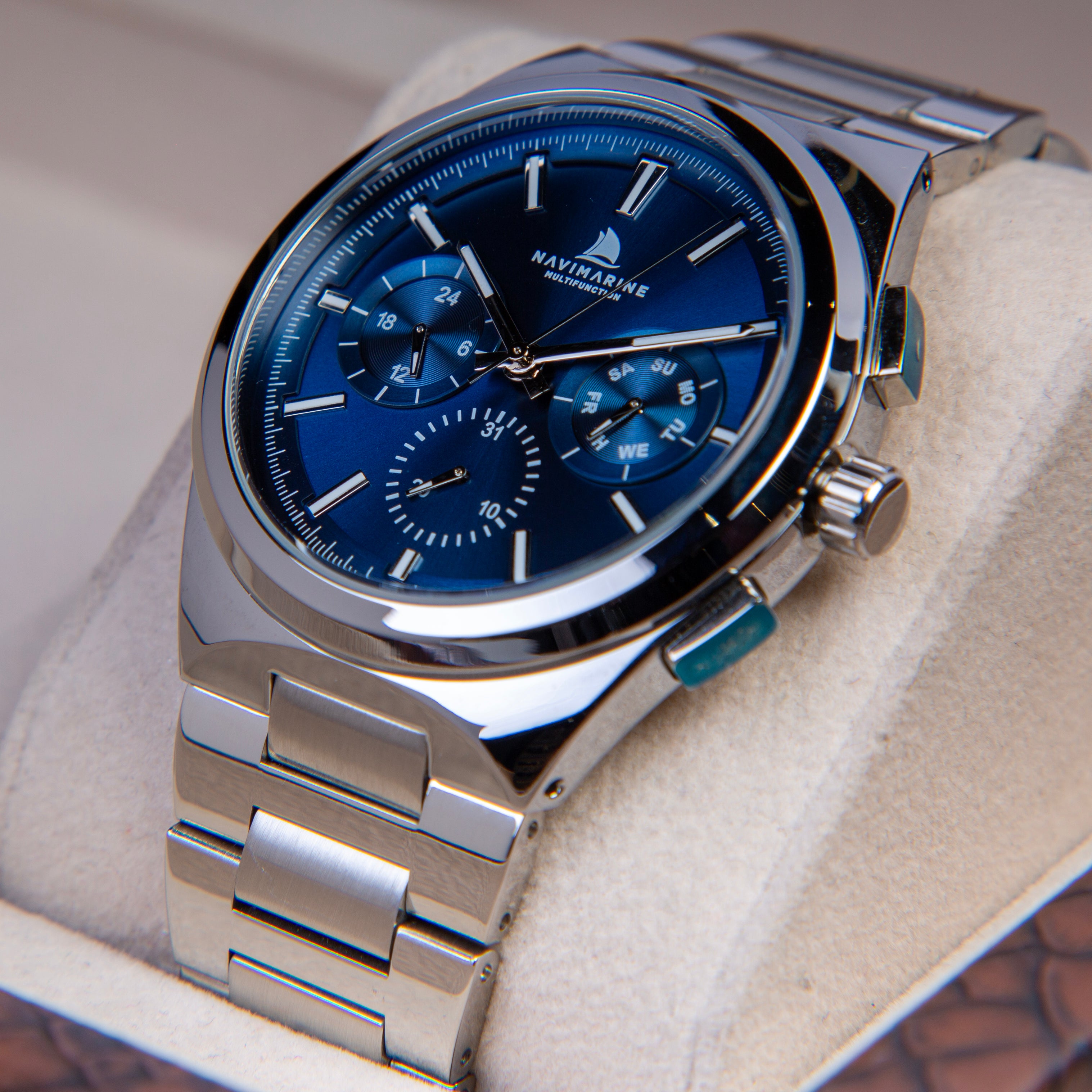 Silver watch with blue face on a white cushion